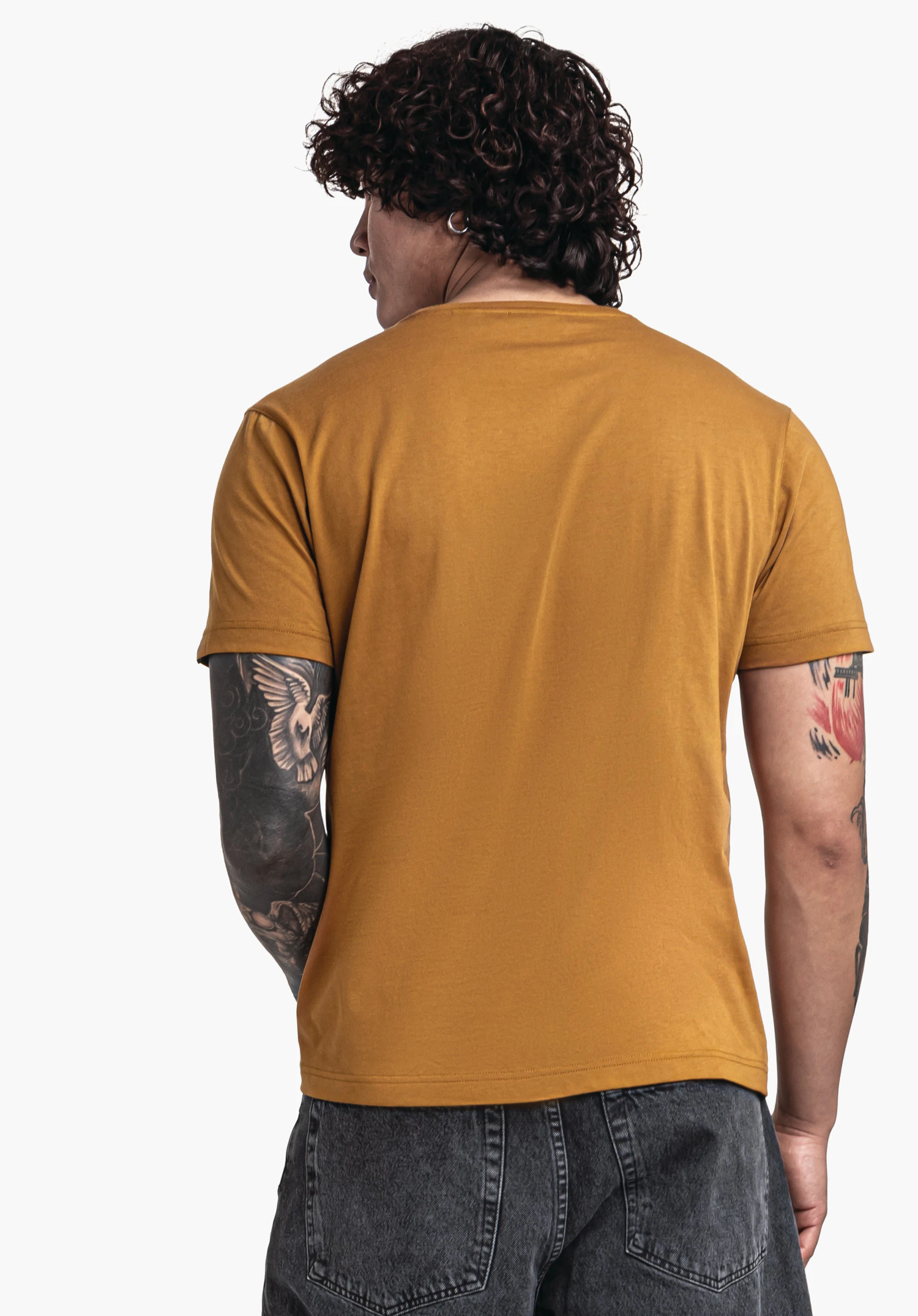 T Shirt Style Collada MNS t-shirt jaune foncé porté par une personne en vue de dos; bras relâchés, tatouages visibles; fond blanc lumineux.