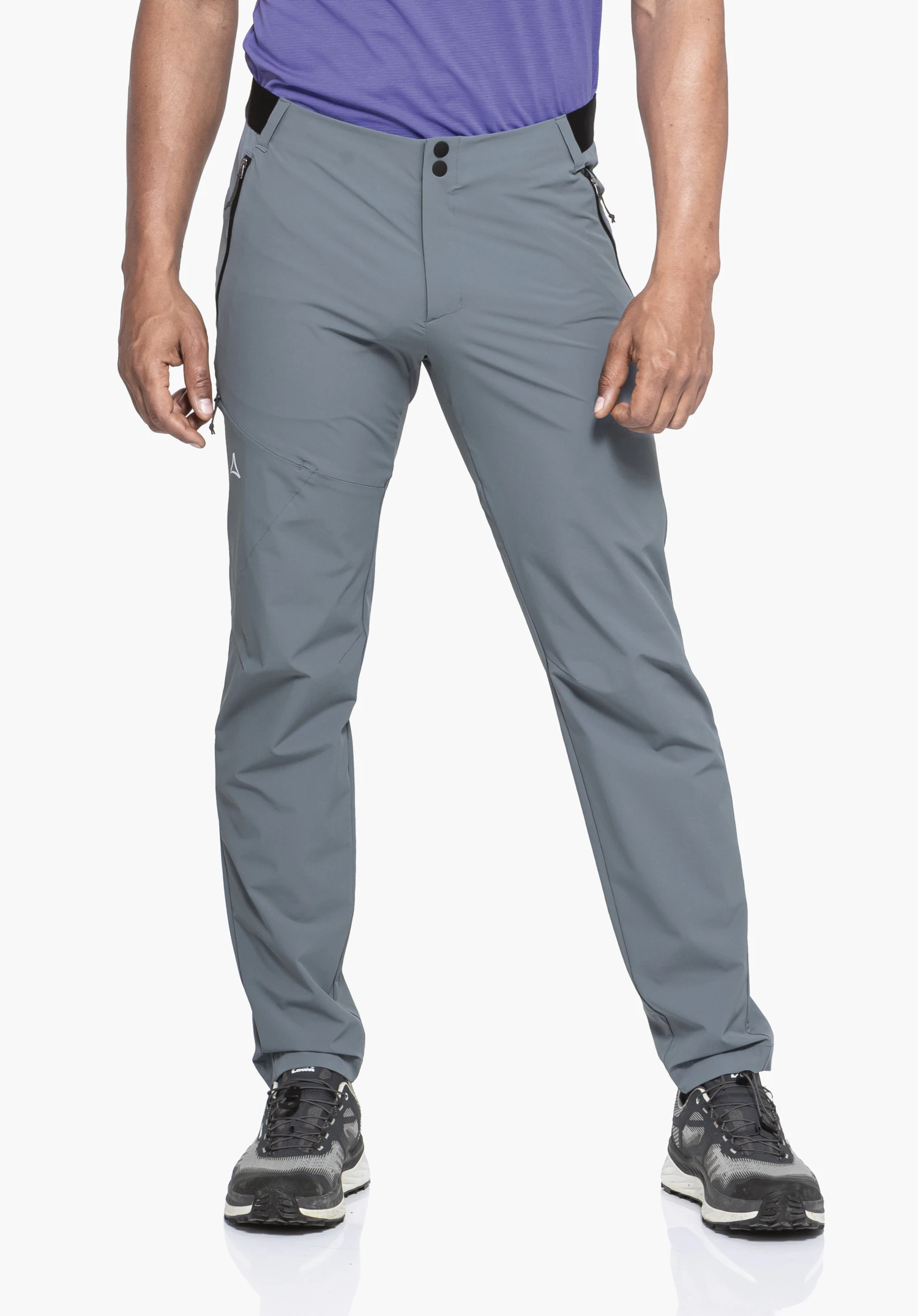 Pants Style Blaustein MNS in Grau. Ein Model präsentiert die Hose frontal vor einem neutralen Hintergrund. Die Hose sitzt passgenau, das kleine Schöffel-Logo am Oberschenkel ist gut erkennbar.
