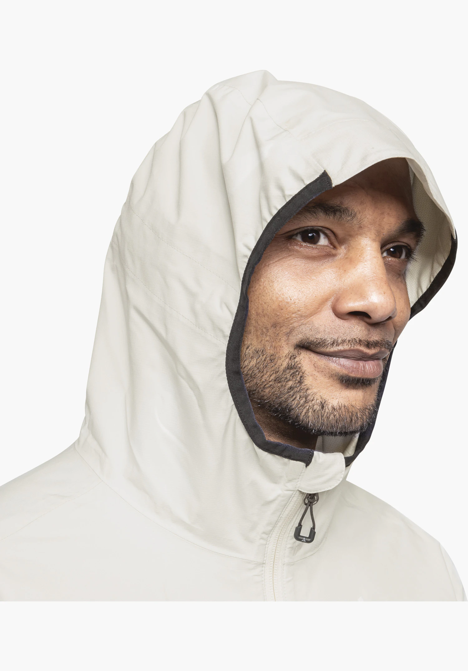 Jacket Style Migandi MNS präsentiert die eng anliegende Kapuze in der Farbe Natur mit einer dunklen Einfassung sowie das Reißverschluss-Detail mit markantem Zipper-Puller am Kragen. Nahaufnahme vor weißem Hintergrund.