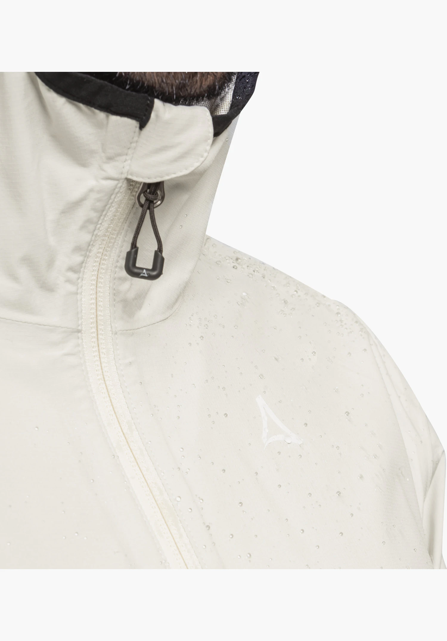 Jacket Style Migandi MNS in der Farbe Natur, mit Fokus auf den Reißverschluss, den wasserabweisenden Stoff mit abperlenden Tropfen und das dezente Schöffel-Logo. Nahaufnahme vor weißem Hintergrund.