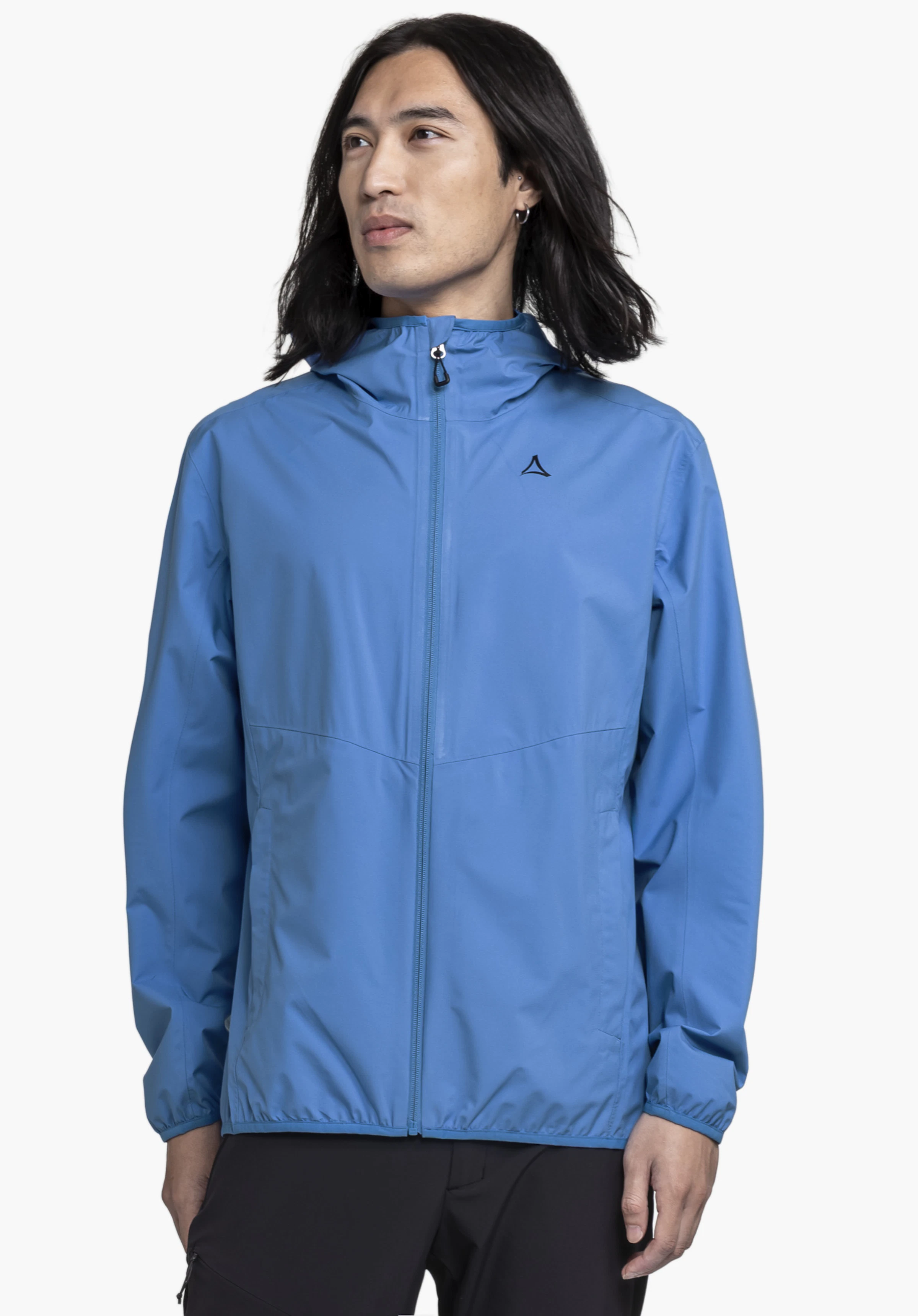 Jacket Style Migandi MNS in Blau, getragen von einem Model. Das Model steht in Frontalansicht, blickt leicht zur Seite und hat die Arme locker hängen. Auf der linken Brust der Jacke ist deutlich das Schöffel-Logo zu erkennen. Präsentiert vor einem neutralen Hintergrund.