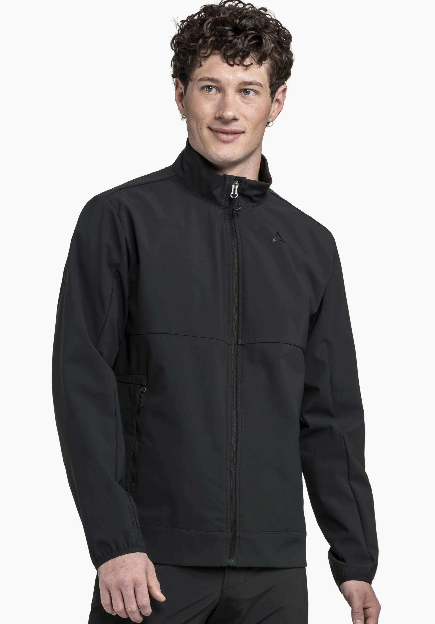 Softshell Jk Style Mirusha MNS en noir. Un mannequin porte la veste fermée en vue de face, laissant apparaître le col montant et le logo Schöffel sur la poitrine gauche. Le mannequin se tient devant un fond neutre.