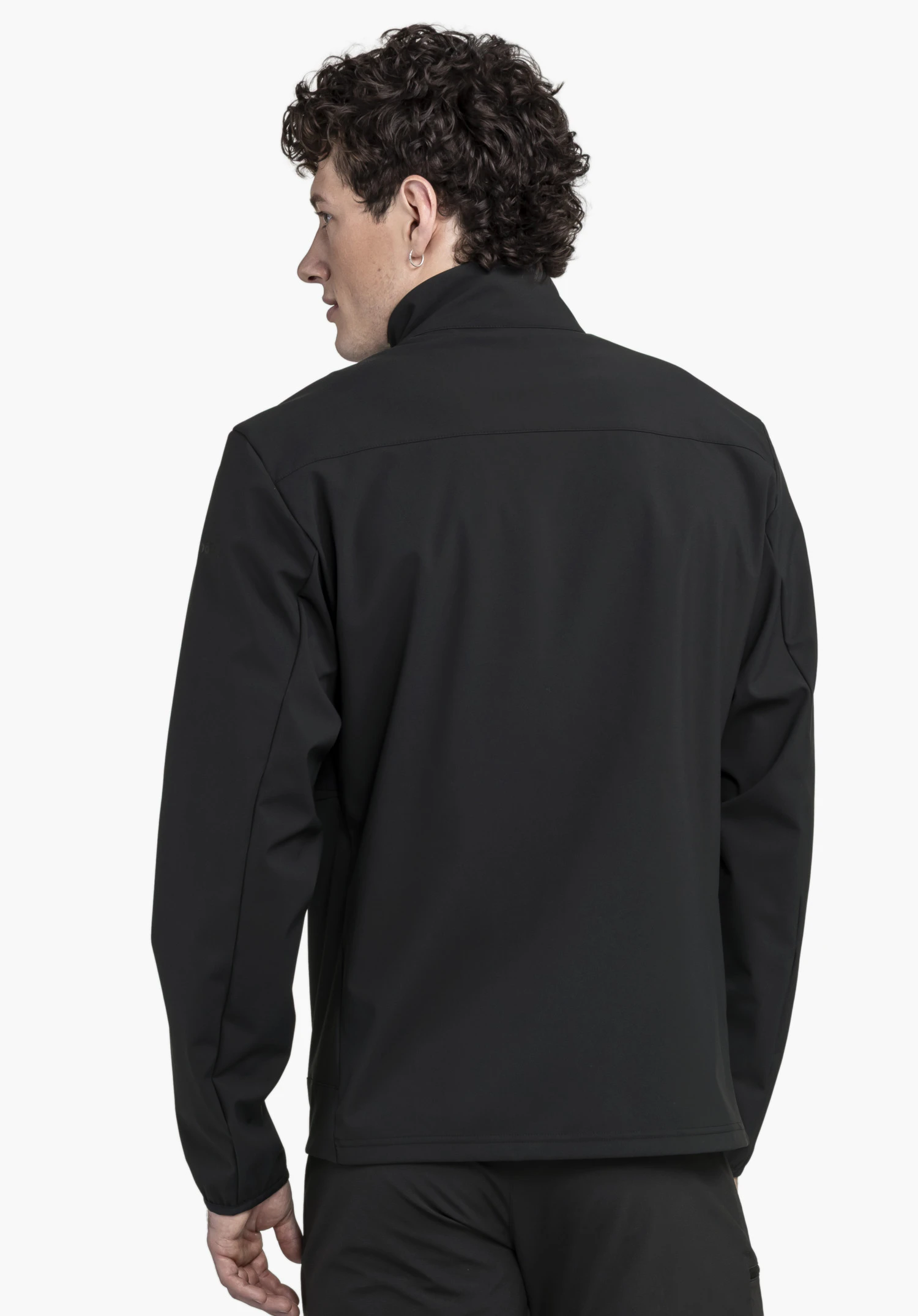 Softshell Jk Style Mirusha MNS portée par un mannequin vu de dos. La veste noire présente un design épuré avec un col montant, tandis que le mannequin se tient légèrement de biais et regarde sur le côté, présentée sur un fond neutre.