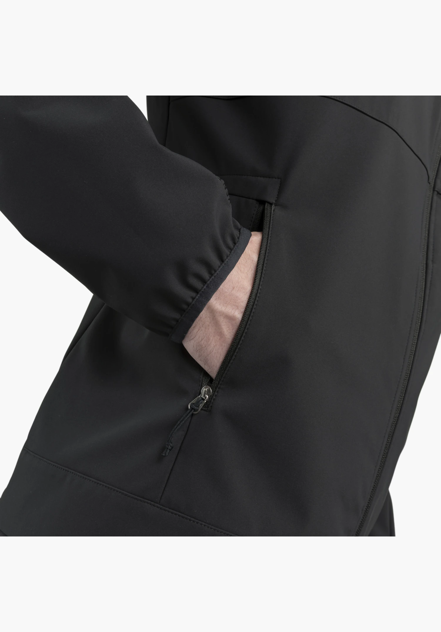 Softshell Jk Style Mirusha MNS. Détail de la poche latérale zippée avec cordon tire-zip contenant une main, ainsi que du poignet élastique sur le tissu noir. Gros plan sur fond blanc.