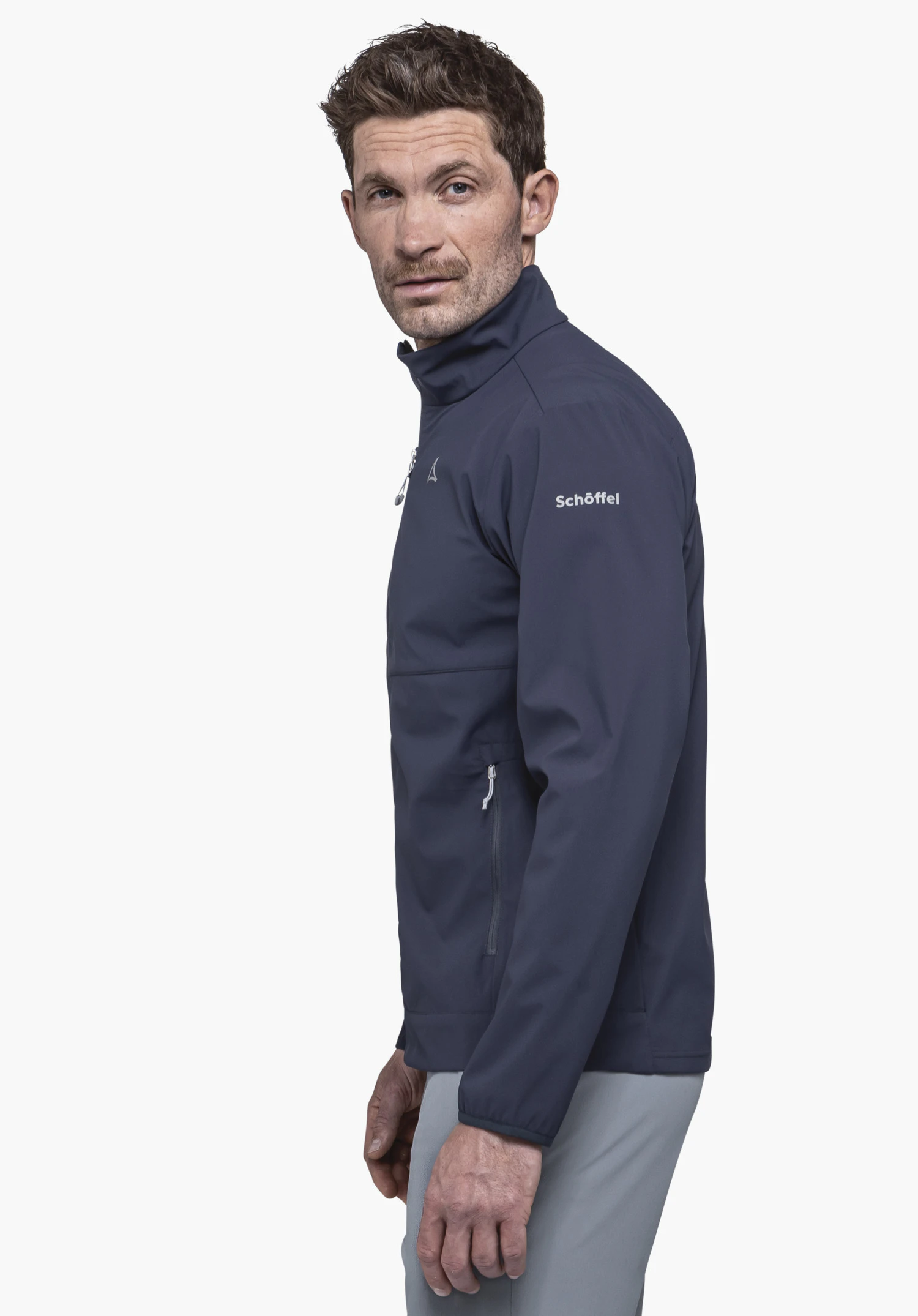Softshell Jk Style Mirusha MNS is worn by a model standing sideways. The blue jacket features the Schöffel logo on the sleeve and is presented against a neutral background.