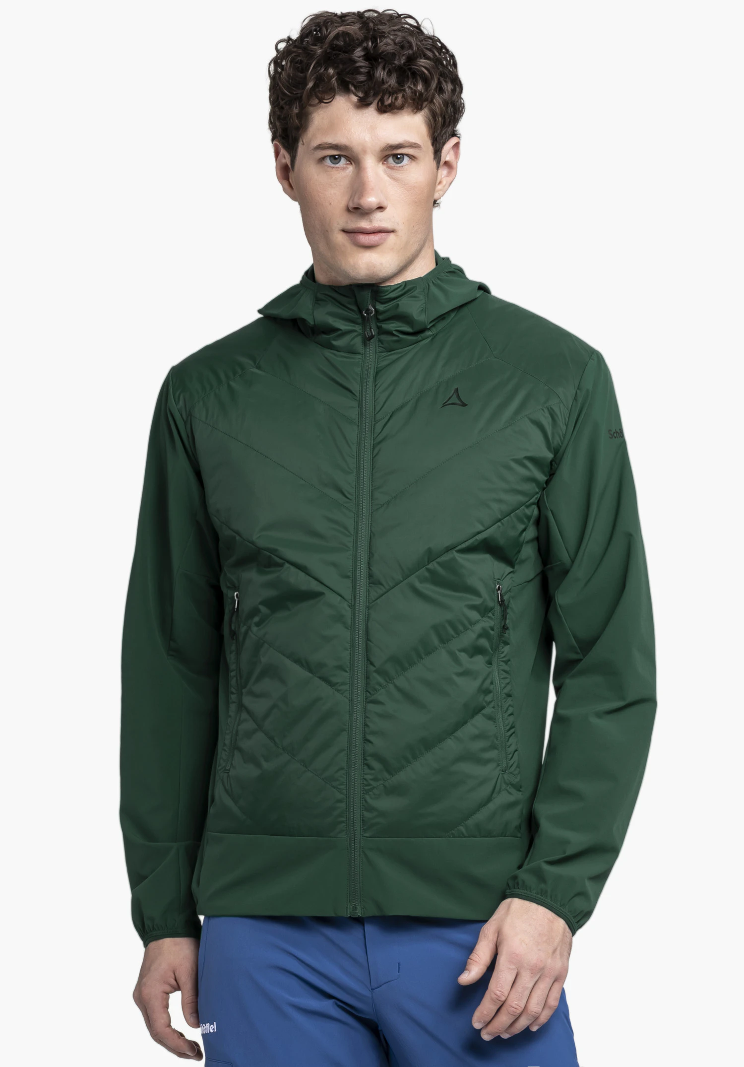 Hybrid Jk Style Blaueis MNS, worn by a male model standing front-on and looking directly at the camera. The green jacket features a distinctive quilted pattern on the front and the Schöffel logo on the left chest, presented against a neutral background.