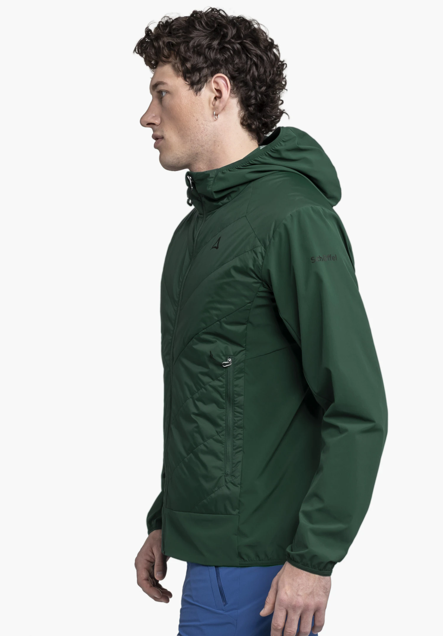 Hybrid Jk Style Blaueis MNS worn by a model standing sideways. The green jacket features the Schöffel-Logo on the chest and sleeve, presented against a neutral background.