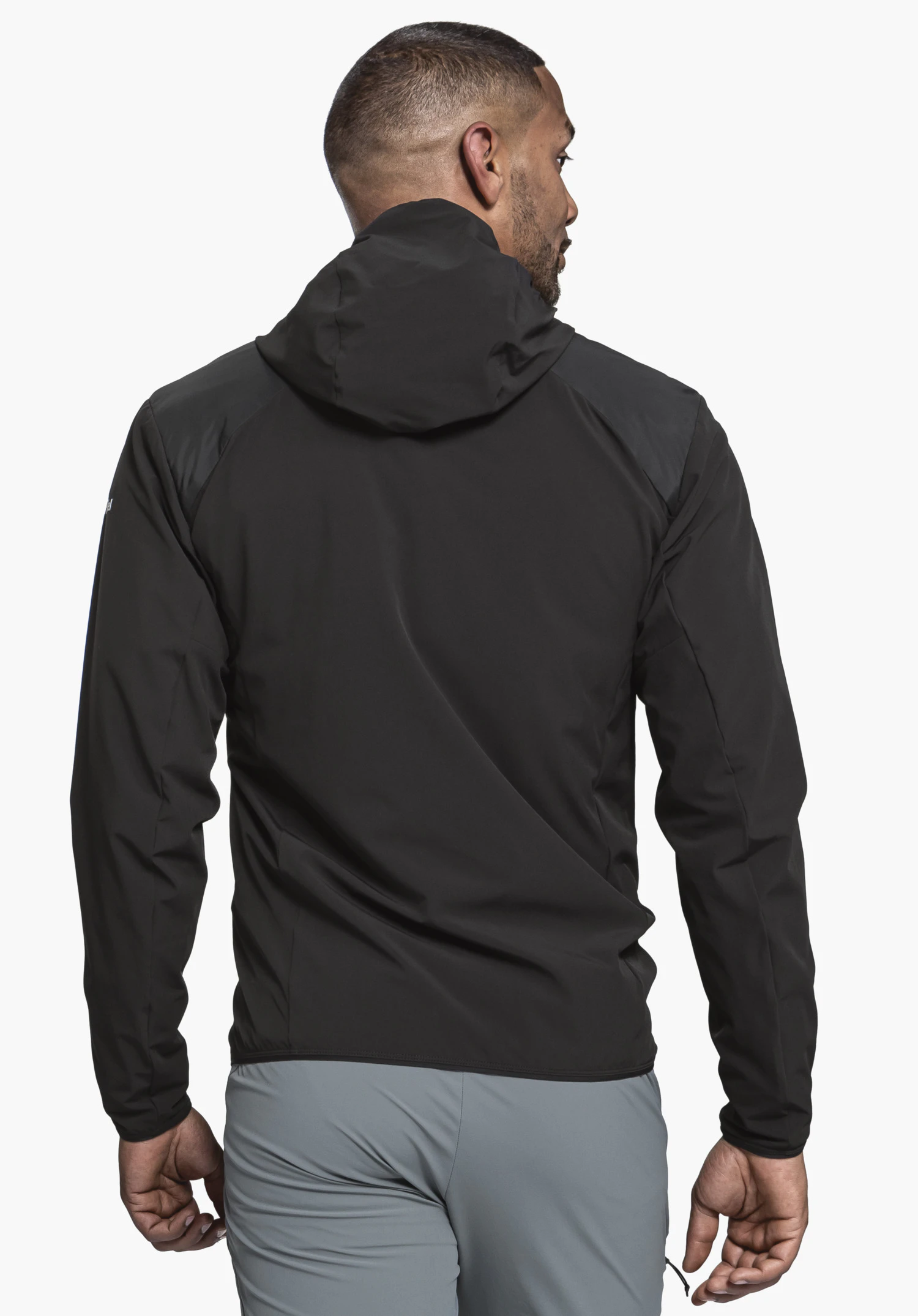 Hybrid Jk Style Blaueis MNS. A model in back view is wearing the black hooded jacket. The Schöffel logo is partially visible on the left sleeve. The model stands in front of a neutral background.