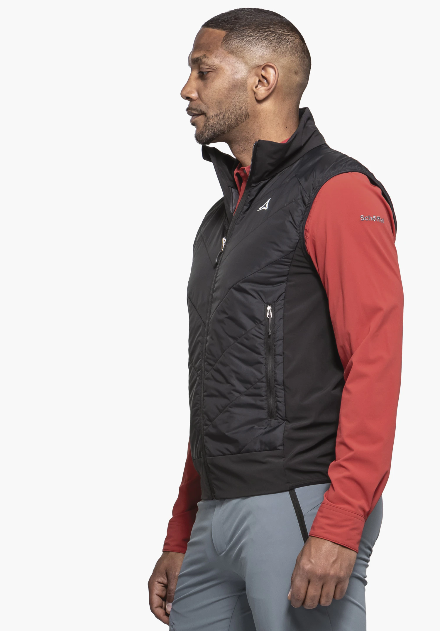 Hybrid Vt Style Blaueis MNS. A model stands sideways presenting the gilet in black with a visible Schöffel logo on the chest. The image shows the garment being worn against a neutral background.