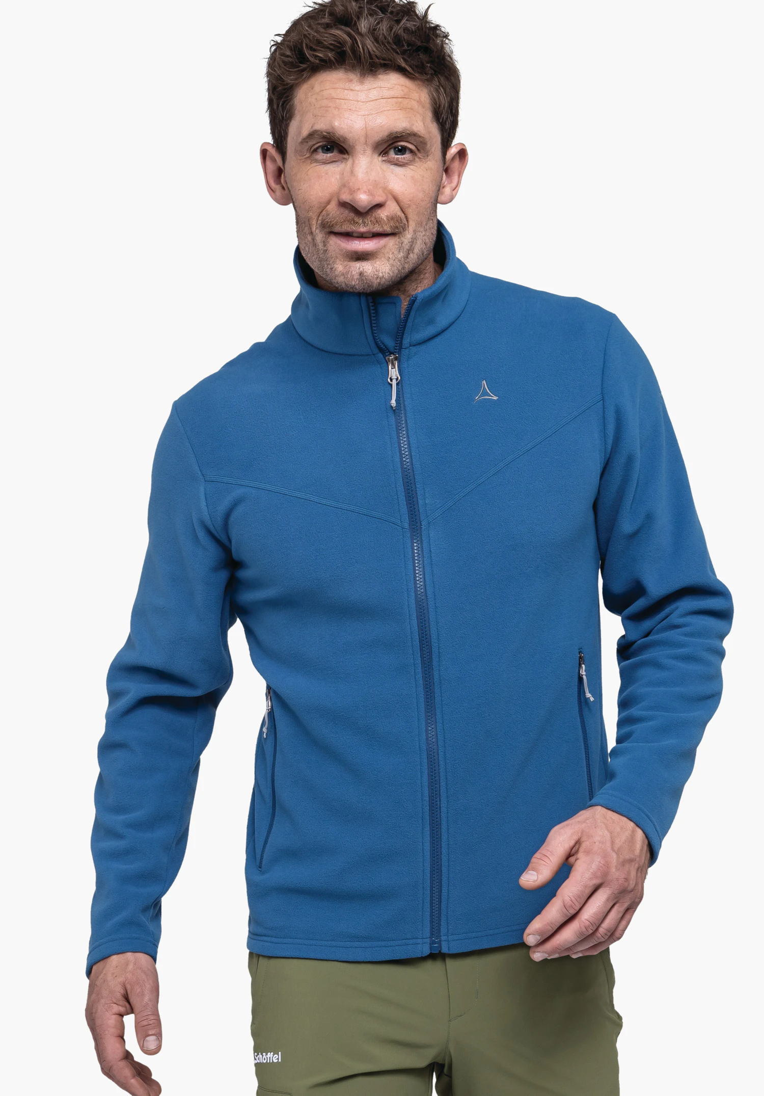 Fleece Jk Style Qutang MNS an einem Model, das frontal steht und in die Kamera blickt. Die blaue Fleecejacke ist geschlossen und zeigt das Schöffel-Logo auf der linken Brust. Das Kleidungsstück wird vor einem neutralen Hintergrund präsentiert.