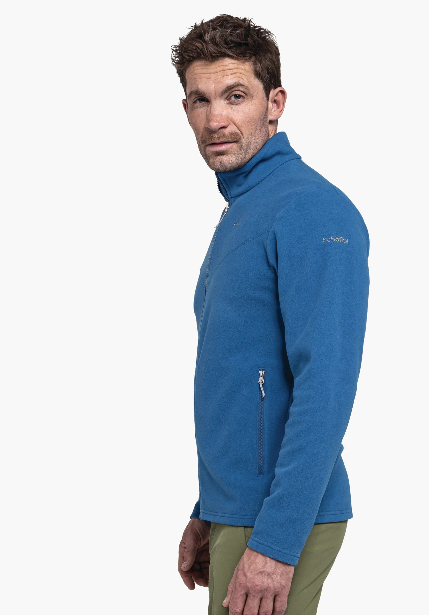 Fleece Jk Style Qutang MNS in blue: The model is positioned in a side profile against a neutral background, showcasing the fleece jacket. The subtle Schöffel logo on the upper arm is clearly visible, highlighting the functional design.