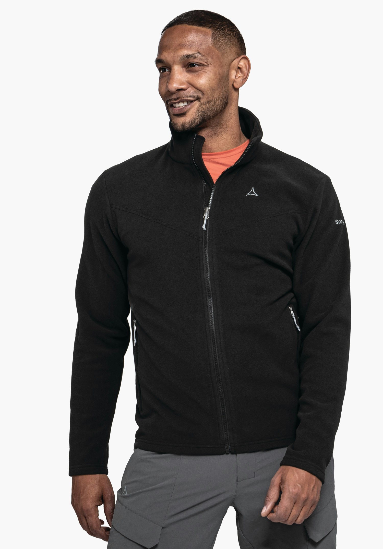 Fleece Jk Style Qutang MNS Schwarze Fleecejacke, Mann trägt sie, Reißverschluss teilweise geöffnet; Schöffel-Logo auf Brust; Text: "Schöffel" auf rechtem Ärmel; hellorange Shirt sichtbar; graue Hose; weißer Hintergrund.
