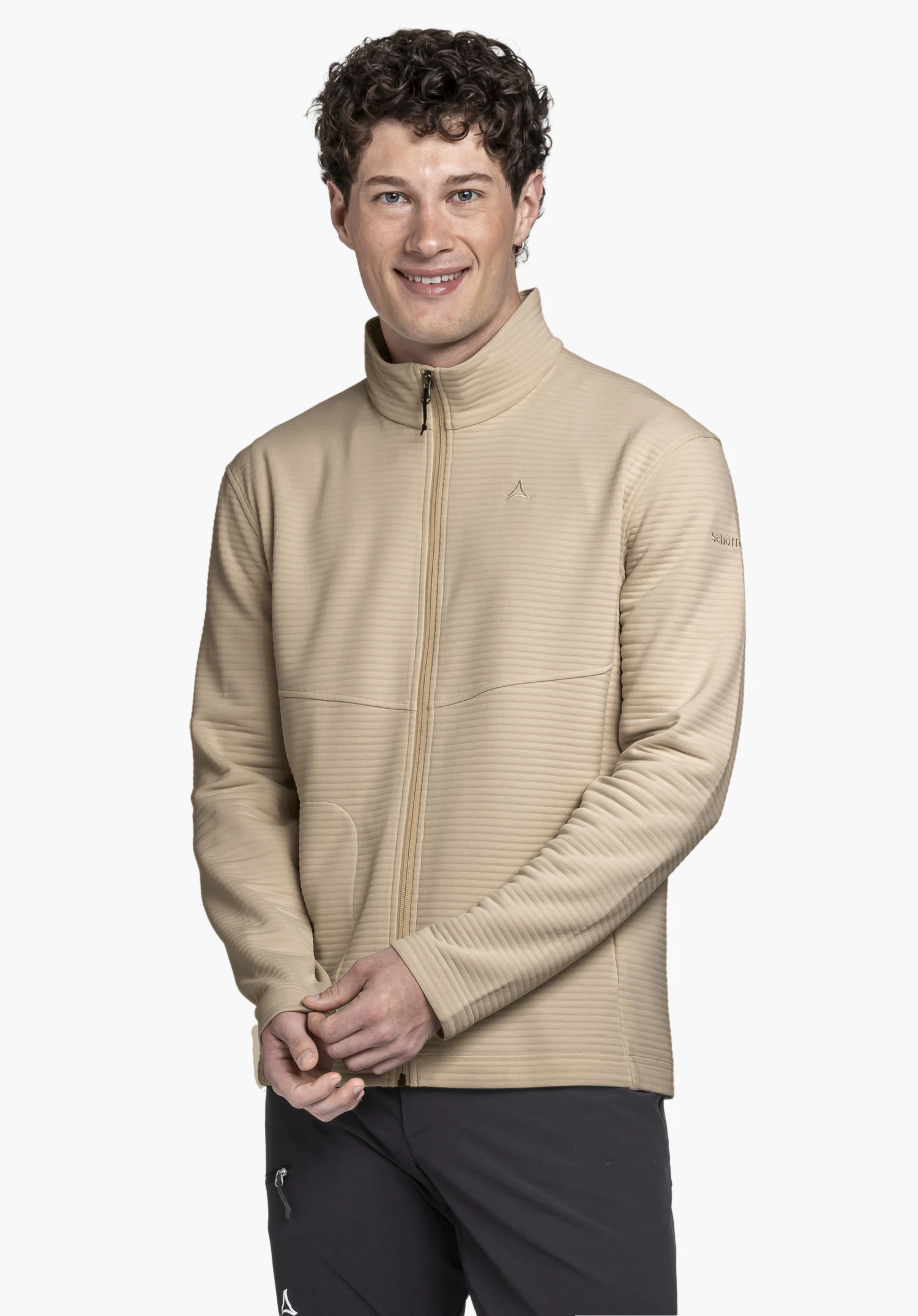 CIRC Fleece Jk Style Smue MNS. Un mannequin souriant porte la veste polaire beige, se tenant face à la caméra avec ses mains jointes devant lui. Le Schöffel-Logo est visible sur la poitrine gauche et la manche. La vue portée est présentée sur un fond neutre.