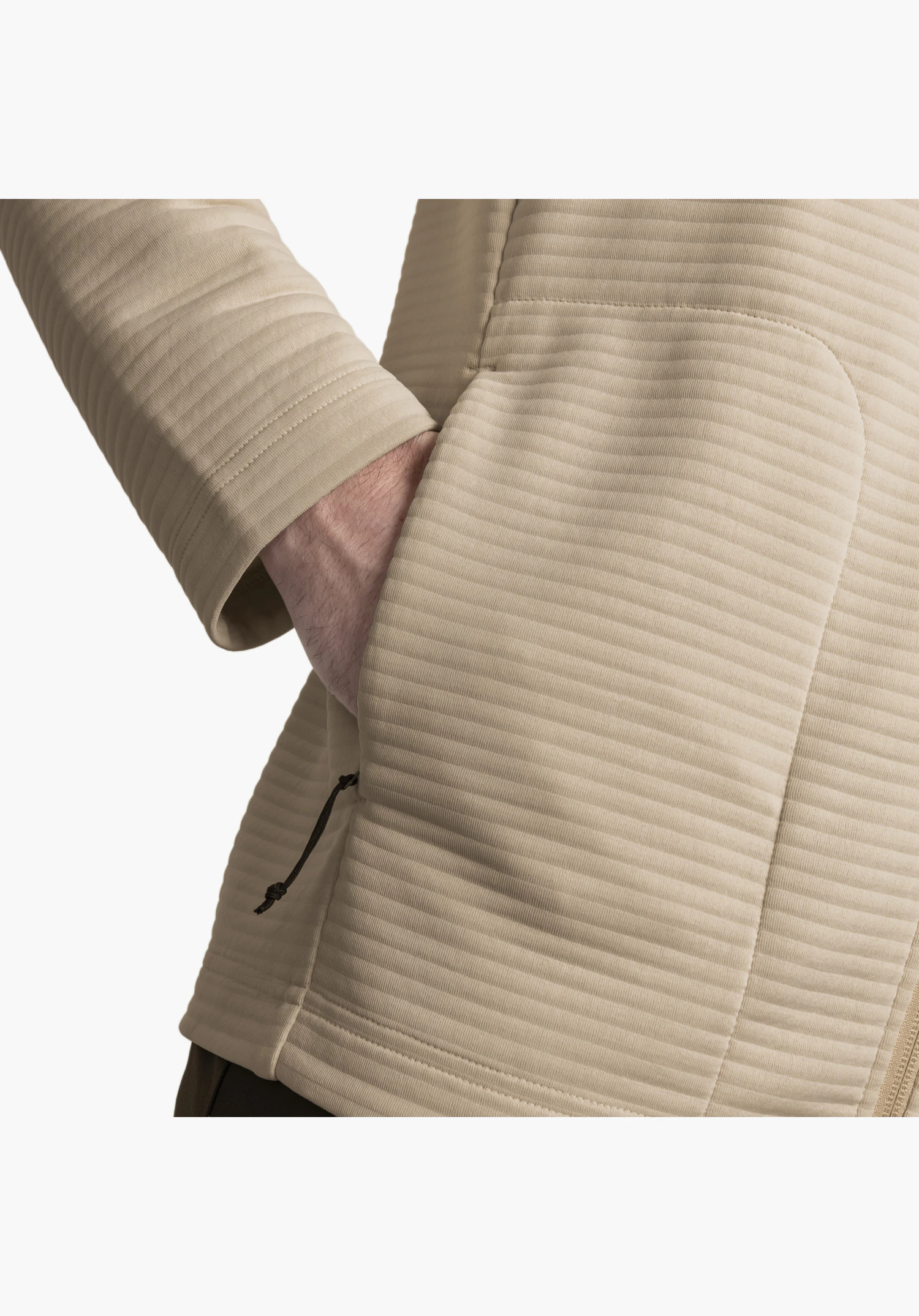 CIRC Fleece Jk Style Smue MNS présente le tissu beige finement nervuré et une poche latérale avec une tirette en cordon, dans laquelle une main est glissée – gros plan sur fond blanc/neutre.
