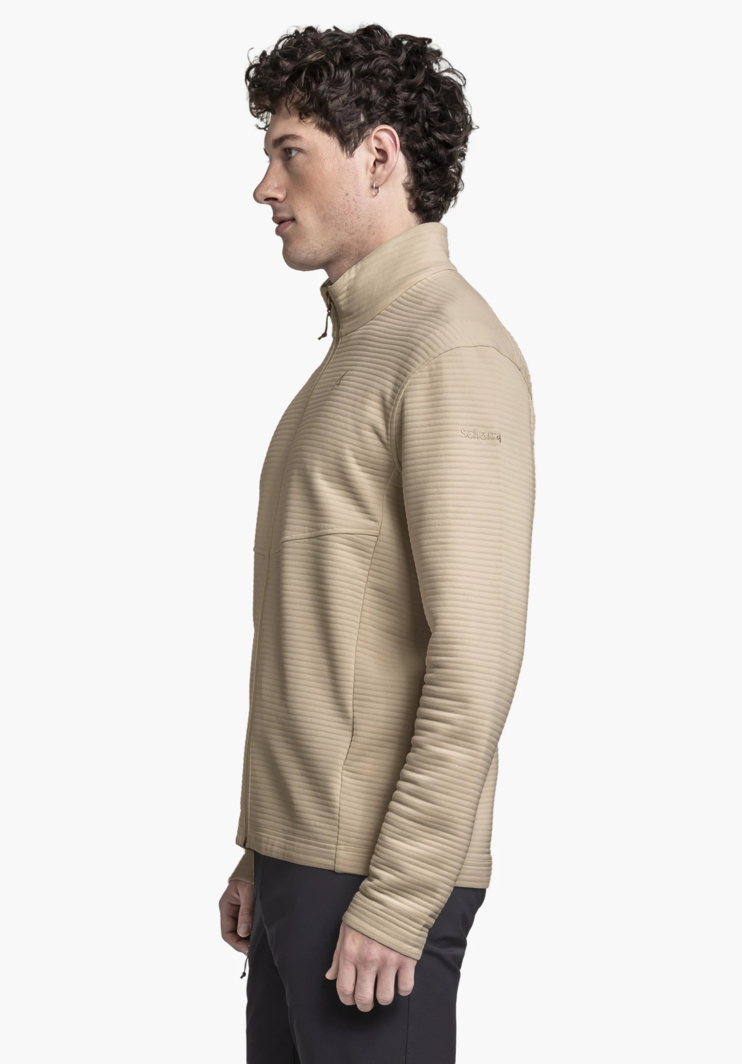 CIRC Fleece Jk Style Smue MNS. Le mannequin pose de profil sur un fond neutre, mettant en valeur la veste polaire en beige. Le logo Schöffel discret est clairement visible sur la manche, soulignant le design épuré.