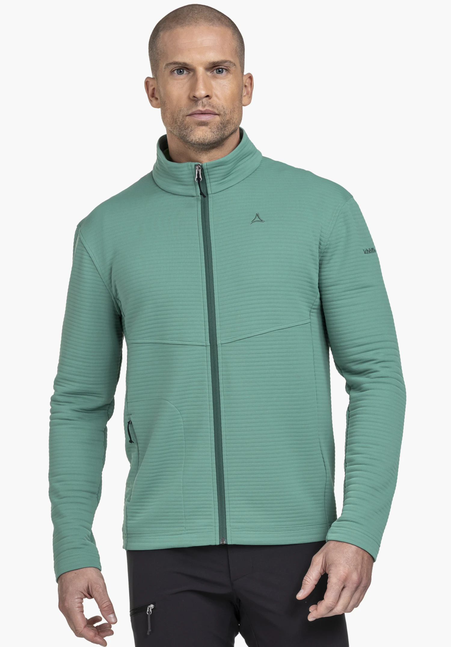 CIRC Fleece Jk Style Smue MNS. Ein männliches Model steht frontal und präsentiert die grüne Fleecejacke mit sichtbarem Schöffel-Logo auf der linken Brust vor einem neutralen Hintergrund.