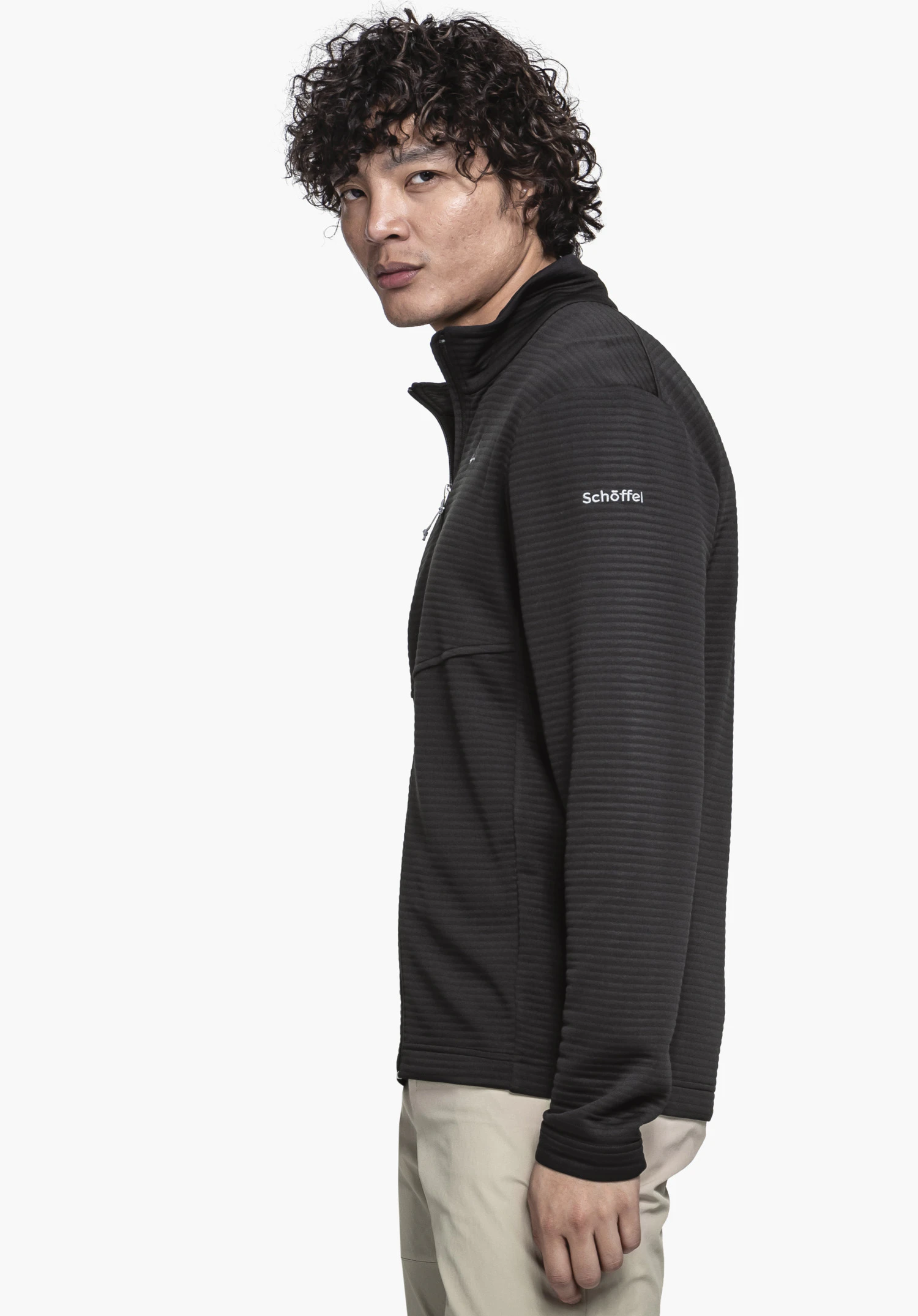CIRC Fleece Jk Style Smue MNS in Schwarz. Ein Model steht in Seitenansicht vor einem neutralen Hintergrund. Die Fleecejacke präsentiert sich in einem klassischen Schwarz, während das weiße Schöffel-Logo am Oberarm dezent hervorsticht.