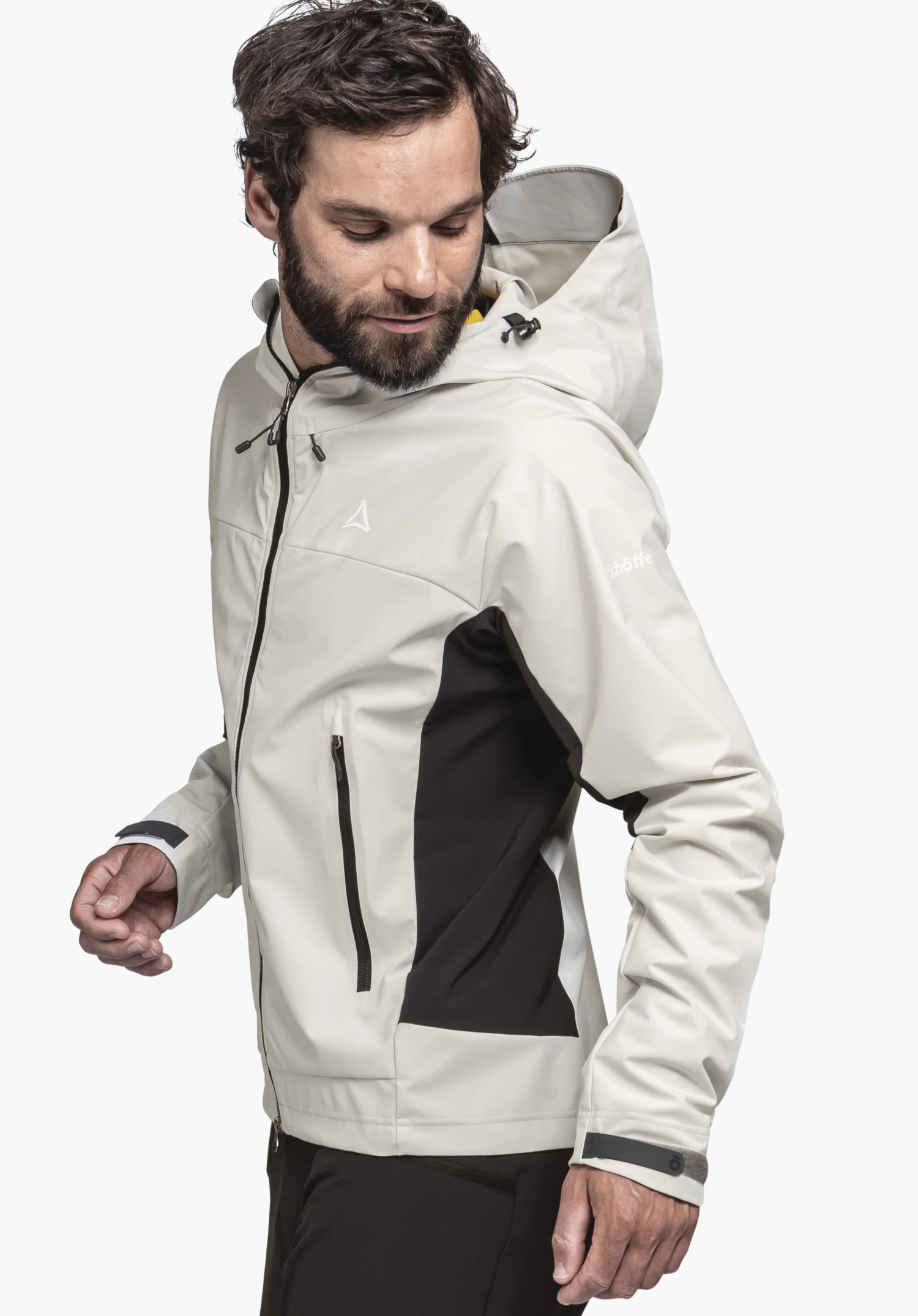 Softshell Jk Style Blaueis MNS worn by a model standing sideways. The jacket in the colour natur features dark contrasting side panels, a hood, and the visible Schöffel logo on the chest and sleeve, presented against a neutral background.