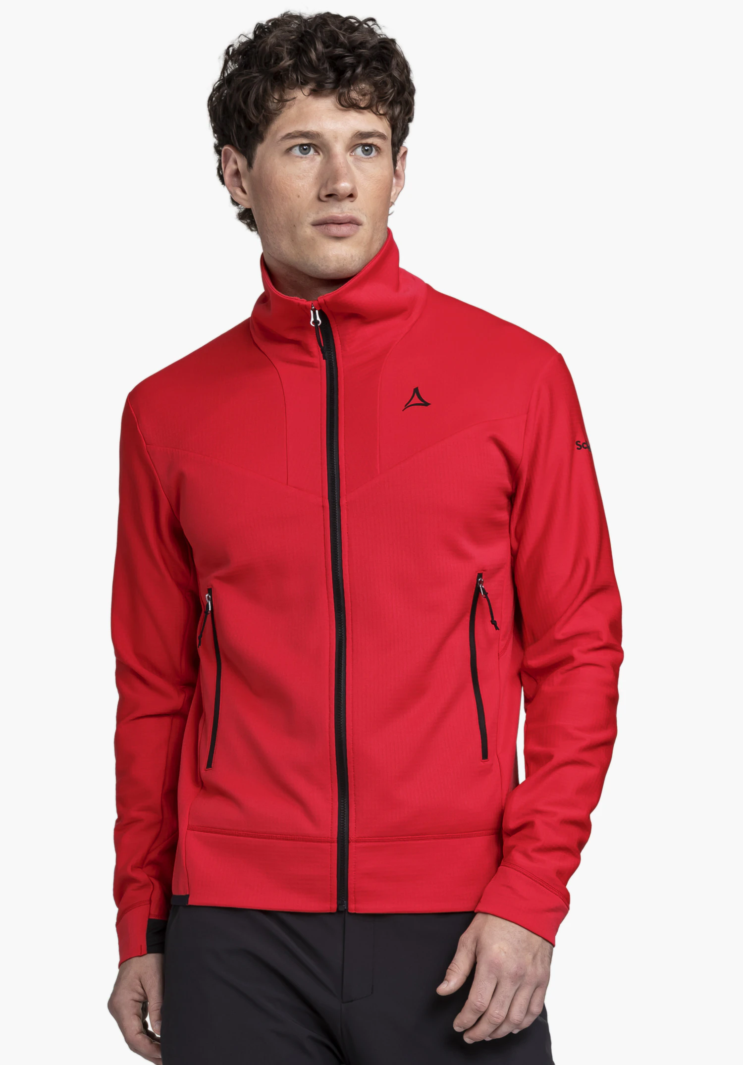 Fleece Jkt Style Blaueis MNS an einem Model, das leicht seitlich steht. Die rote Jacke zeigt sich mit einem schwarzen durchgehenden Frontreißverschluss, schwarzen Reißverschlusstaschen an den Seiten und dem markanten Schöffel-Logo auf der linken Brust sowie dem Ärmel. Die Trageansicht wird vor einem neutralen Hintergrund präsentiert.