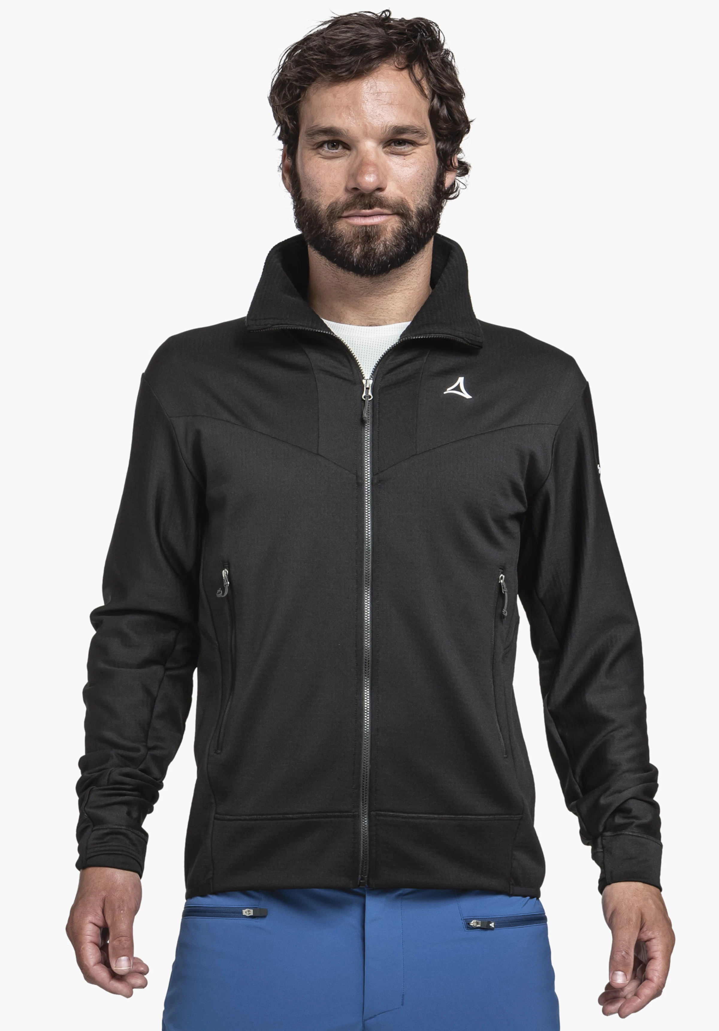 Fleece Jkt Style Blaueis MNS on a model standing facing forwards. The black fleece jacket is shown with a full-length front zip, a stand-up collar and the white Schöffel logo on the left chest, presented against a neutral background.