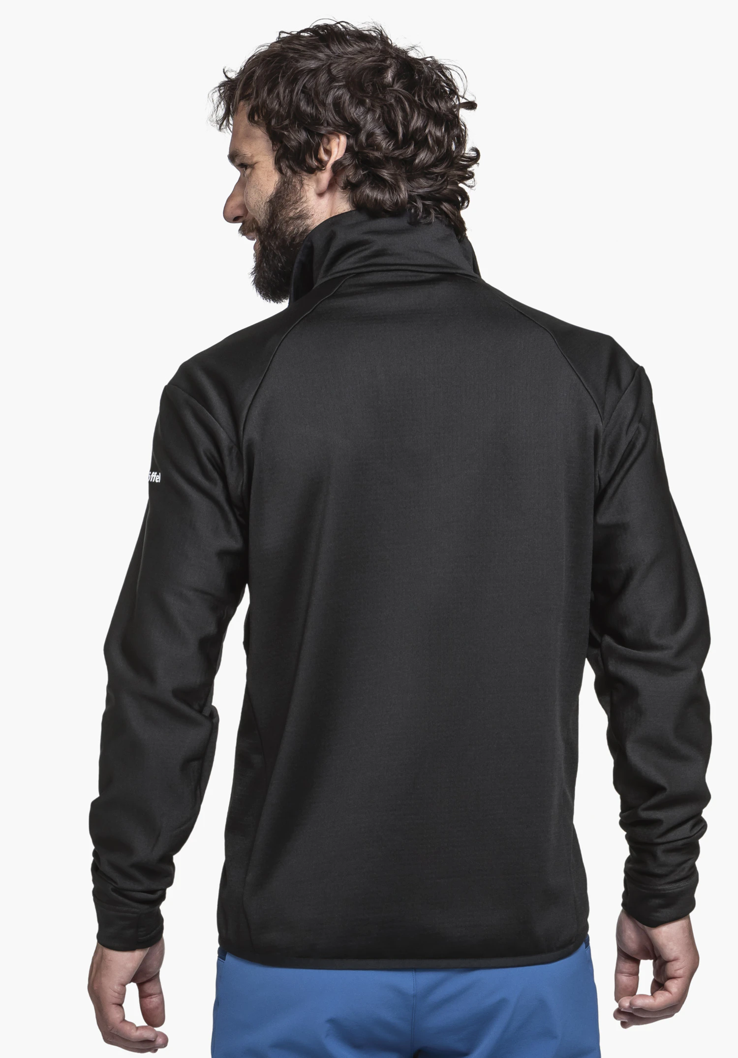 Fleece Jkt Style Blaueis MNS. A model wears the black jacket in a back view, looking slightly over his left shoulder. The white Schöffel logo is visible on the left sleeve. The image shows the model standing against a neutral background.