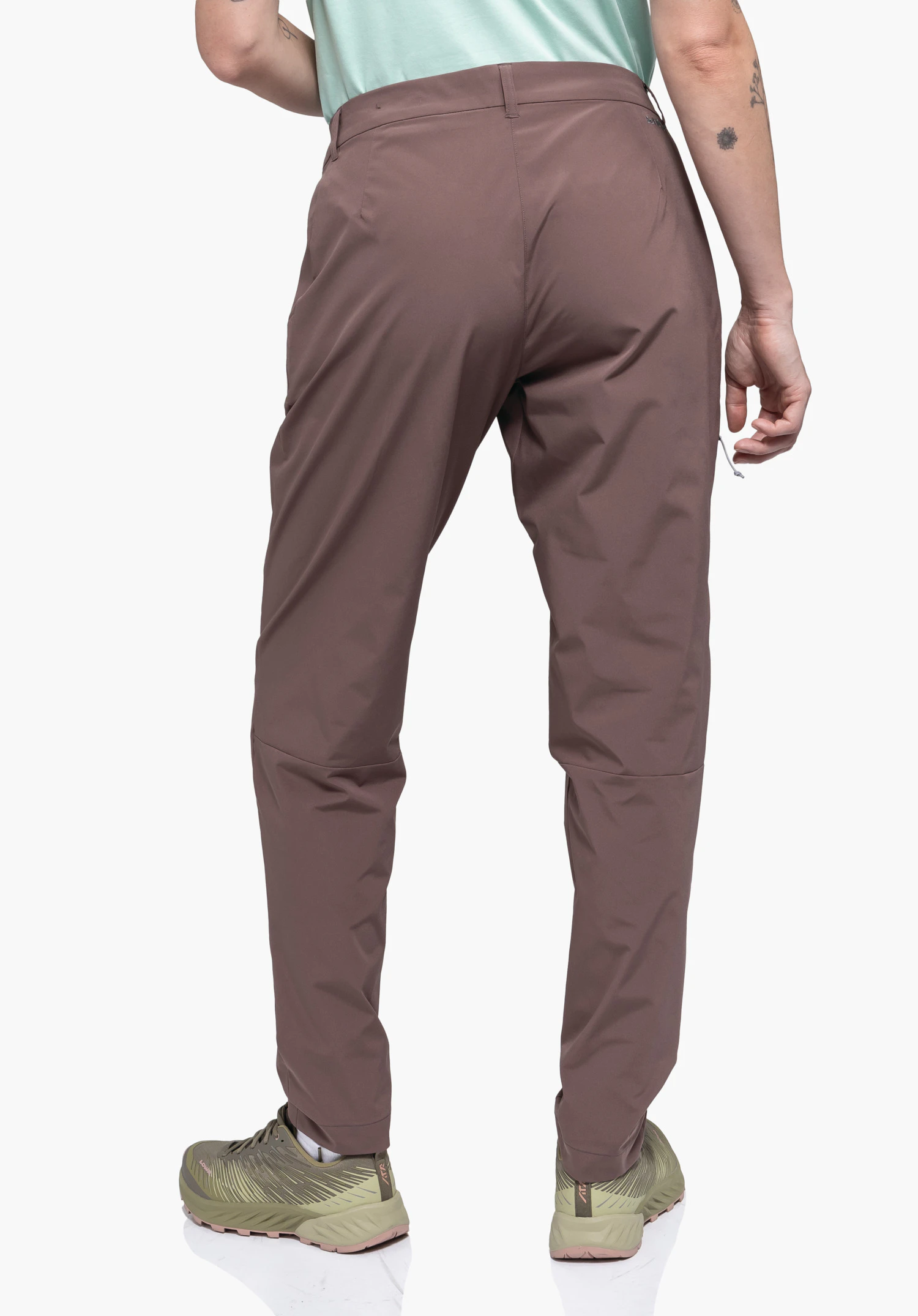 CIRC Pants Style Smue WMS porté par un mannequin en vue de dos. On y voit le pantalon marron avec une coupe confortable et un discret logo Schöffel visible à l'arrière droit de la taille, tandis que le mannequin se tient debout devant un fond neutre.