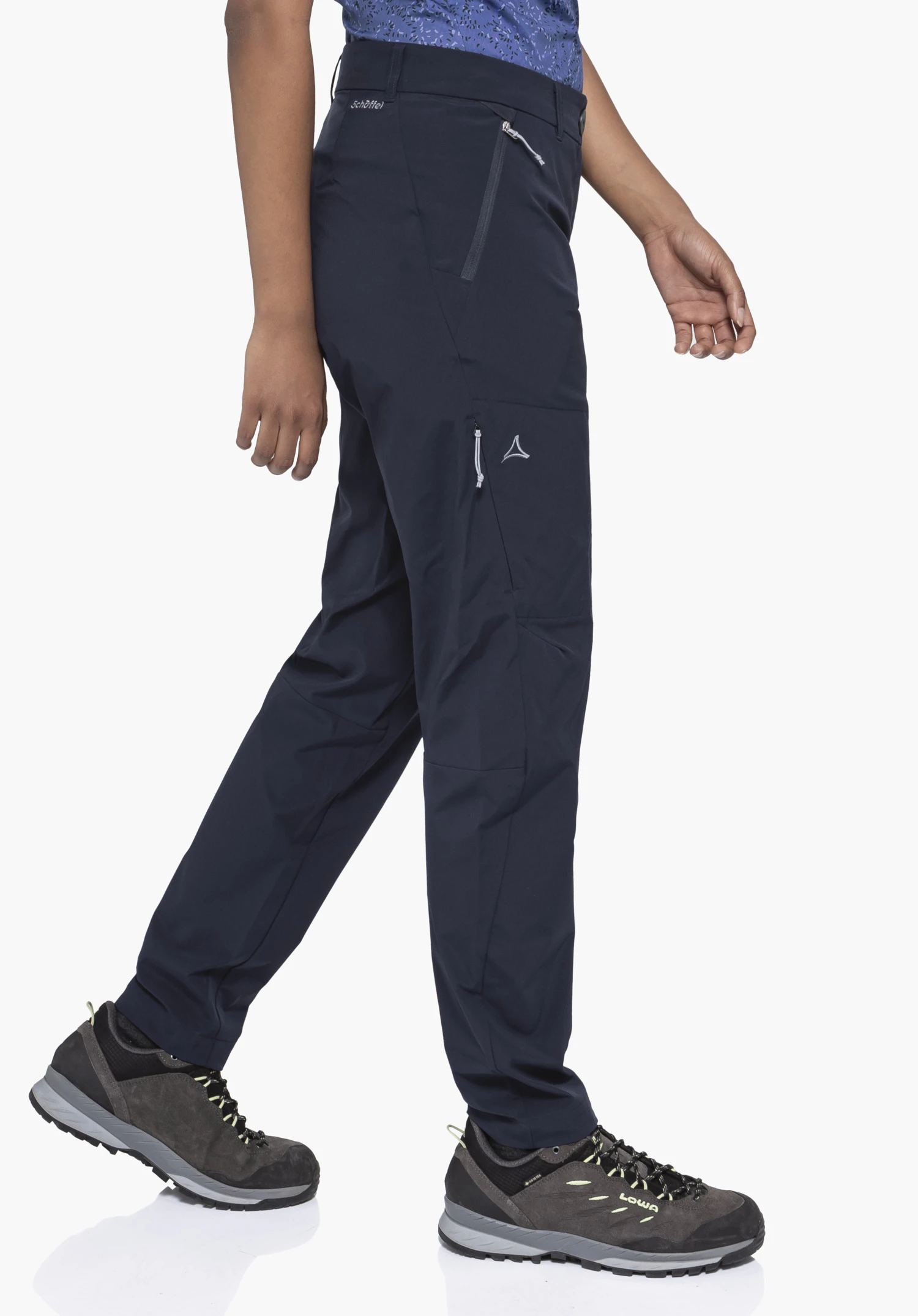 CIRC Pants Style Smue WMS en bleu. Un mannequin se tient de profil dans une position de marche et porte le pantalon avec un Schöffel-Logo visible sur la poche de la jambe devant un fond neutre.