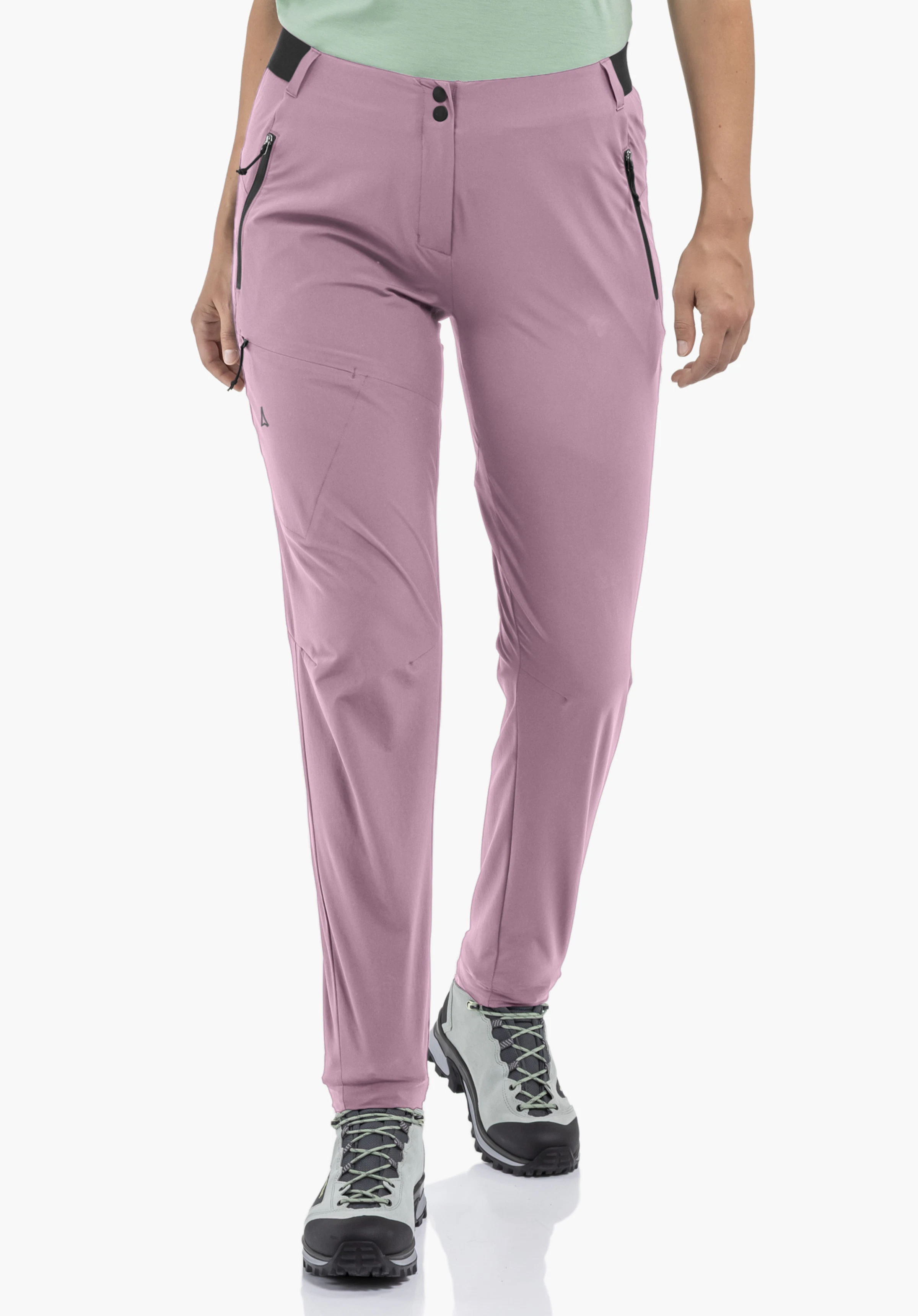 Pants Style Blaustein WMS worn by a model standing in a frontal position. The pink trousers with black zips on the side pockets and the Schöffel logo on the right leg are shown against a neutral background.