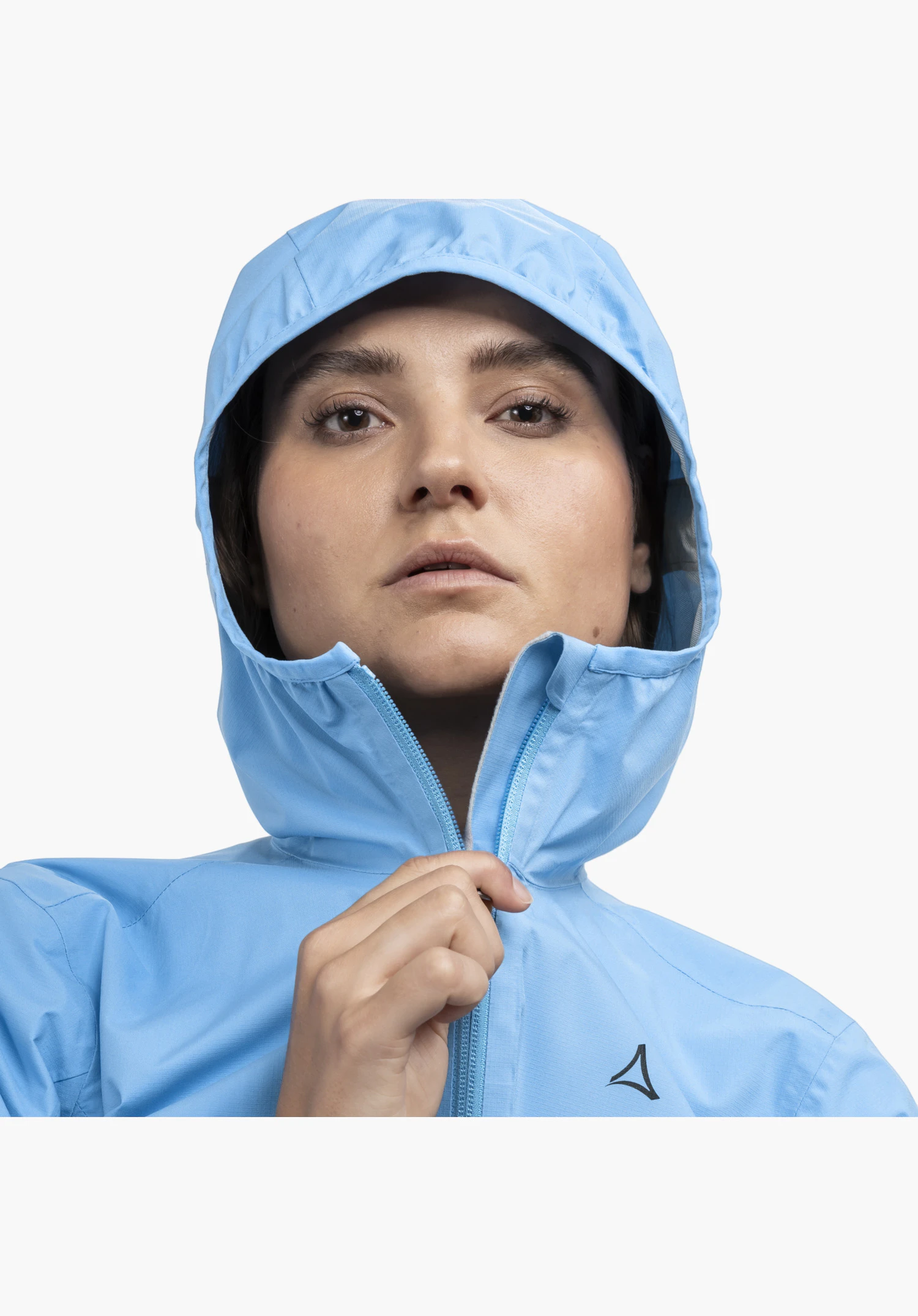 Jacket Style Migandi WMS zeigt Details des blauen Stoffes, eine Hand am Frontreißverschluss der Kapuze und das sichtbare Schöffel-Logo, Nahaufnahme vor weißem/neutralem Hintergrund.