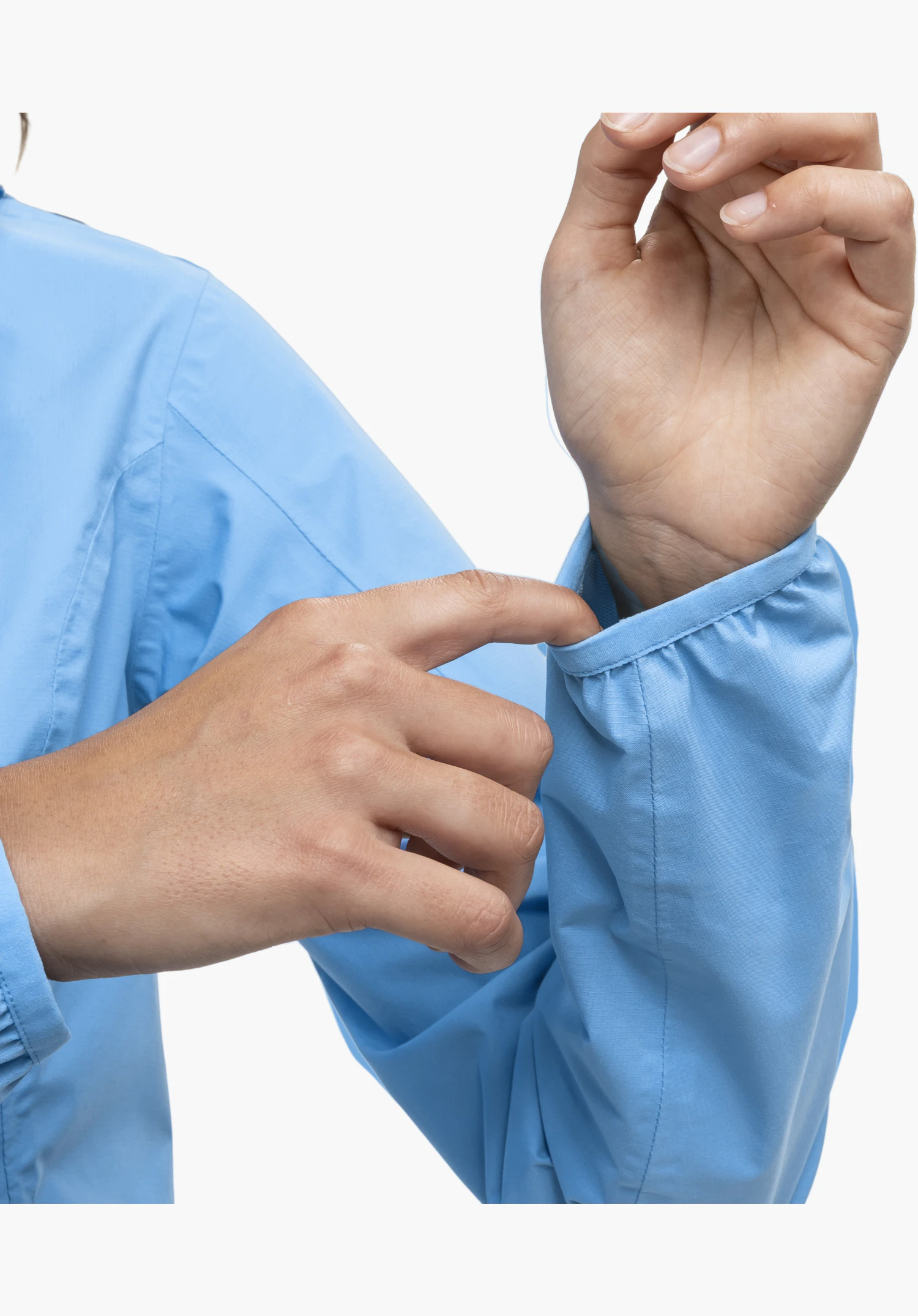 Jacket Style Migandi WMS zeigt den elastischen blauen Ärmelabschluss, der von einer Hand leicht gedehnt wird, um die Flexibilität des Materials zu veranschaulichen. Nahaufnahme vor weißem Hintergrund.
