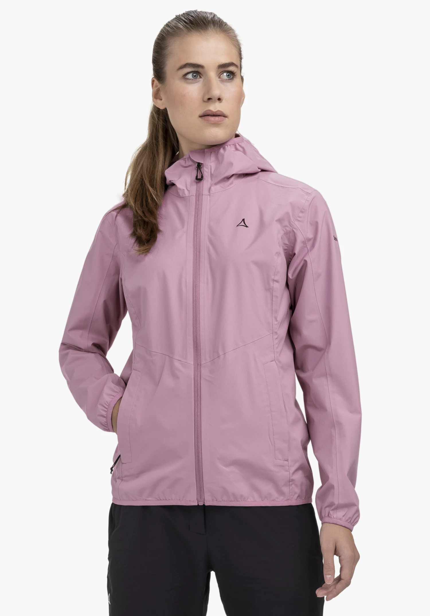 Jacket Style Migandi WMS sur un mannequin se tenant de face avec la main droite dans la poche latérale. La veste rose présente une capuche et le logo Schöffel sur la poitrine gauche, photographiée devant un fond neutre.