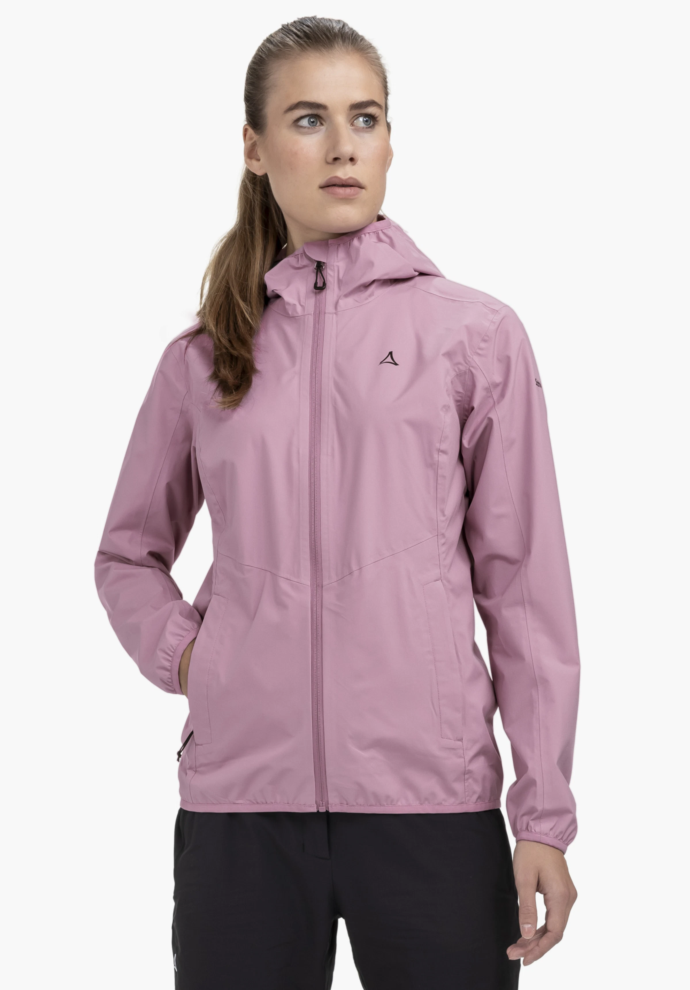 Jacket Style Migandi WMS sur un mannequin se tenant de face avec la main droite dans la poche latérale. La veste rose présente une capuche et le logo Schöffel sur la poitrine gauche, photographiée devant un fond neutre.