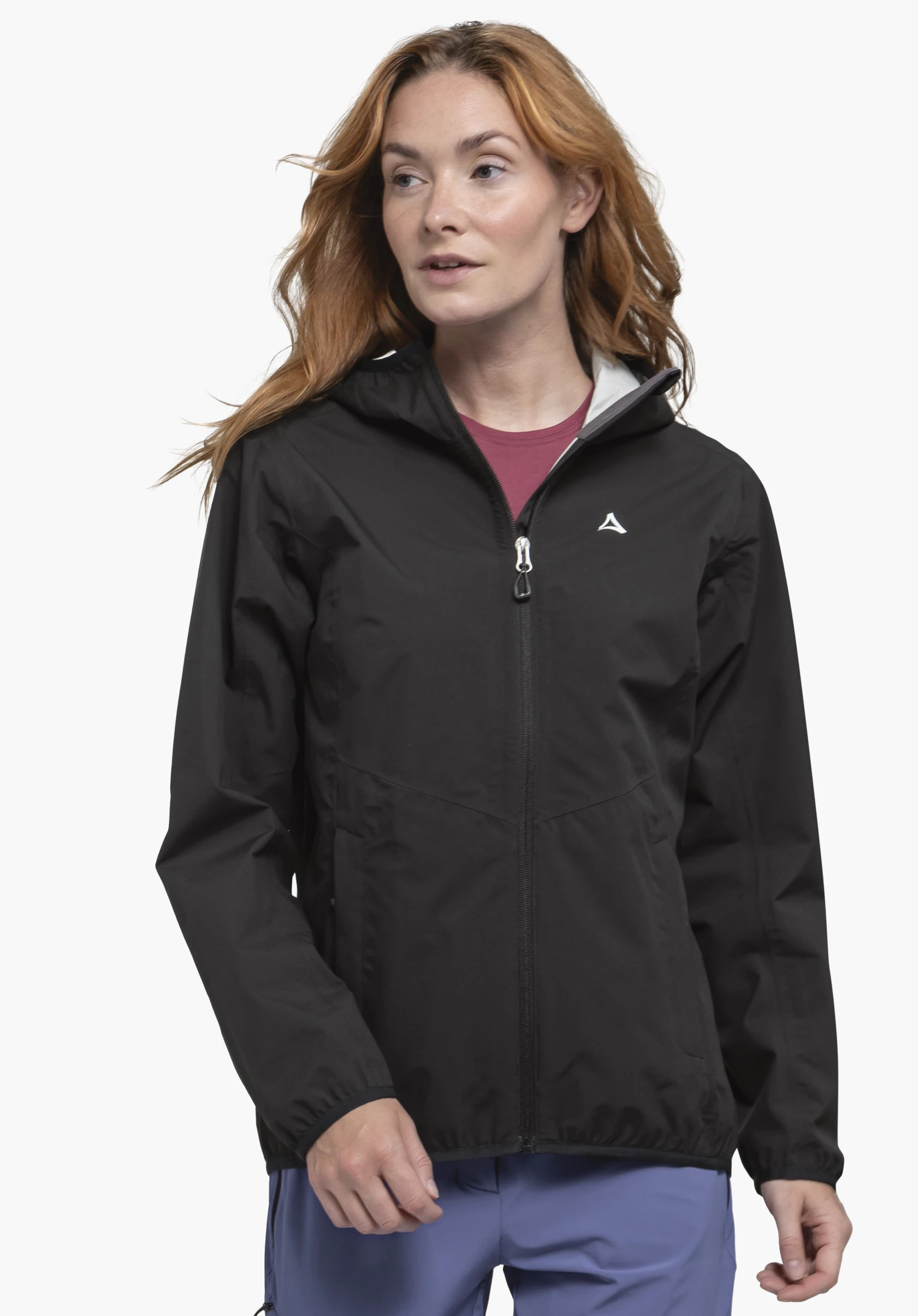 Jacket Style Migandi WMS black rain jacket with zip, worn by a woman; Schöffel logo on the chest; woman looks sideways; wearing a dark red shirt and light blue trousers; neutral white background.