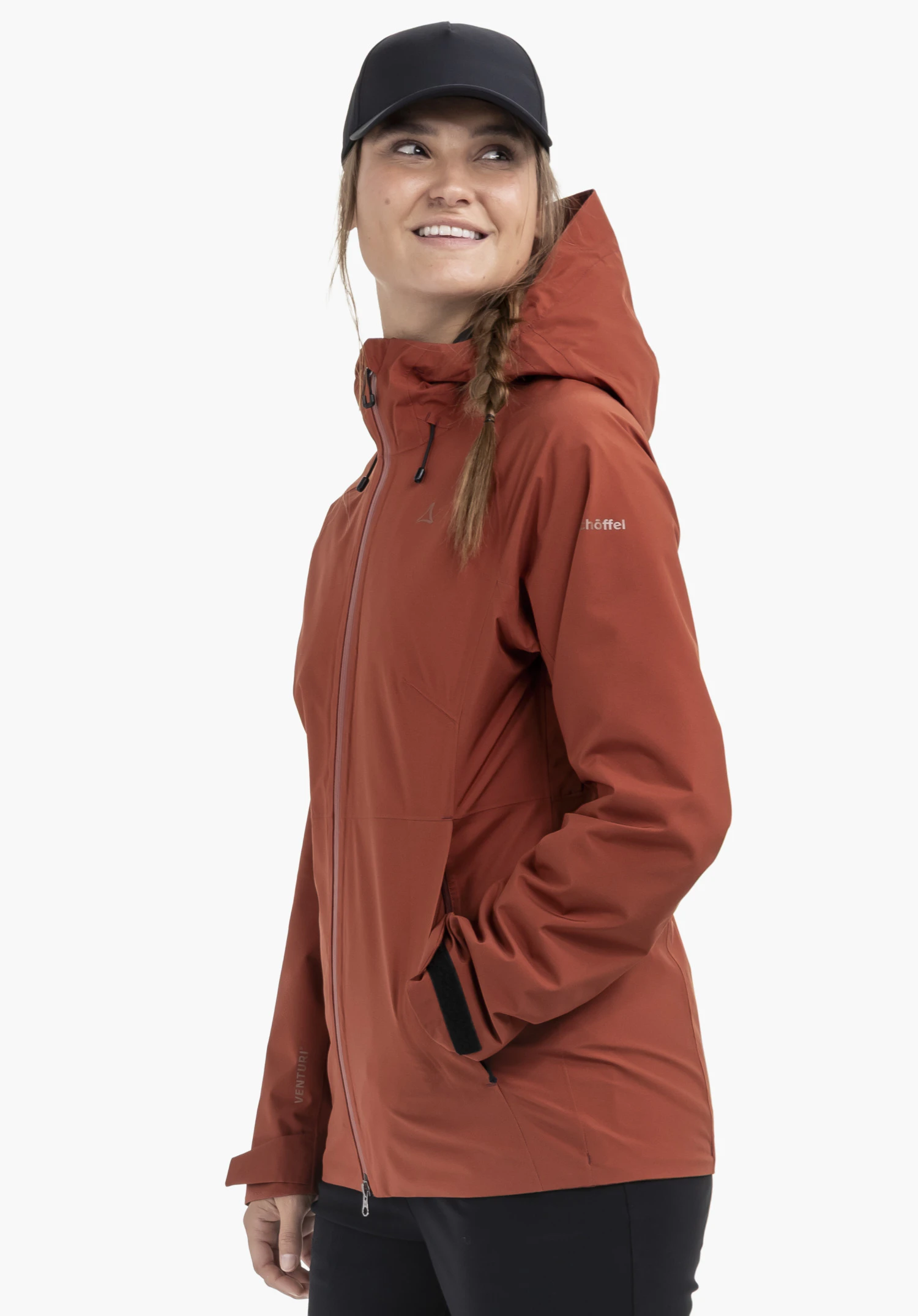 Jacket Style Mauku WMS in red: A woman wears the jacket in a slightly side-facing pose against a neutral background. She looks off to the side with a friendly expression, one hand tucked into the pocket. The subtle Schöffel logo is clearly visible on the chest.
