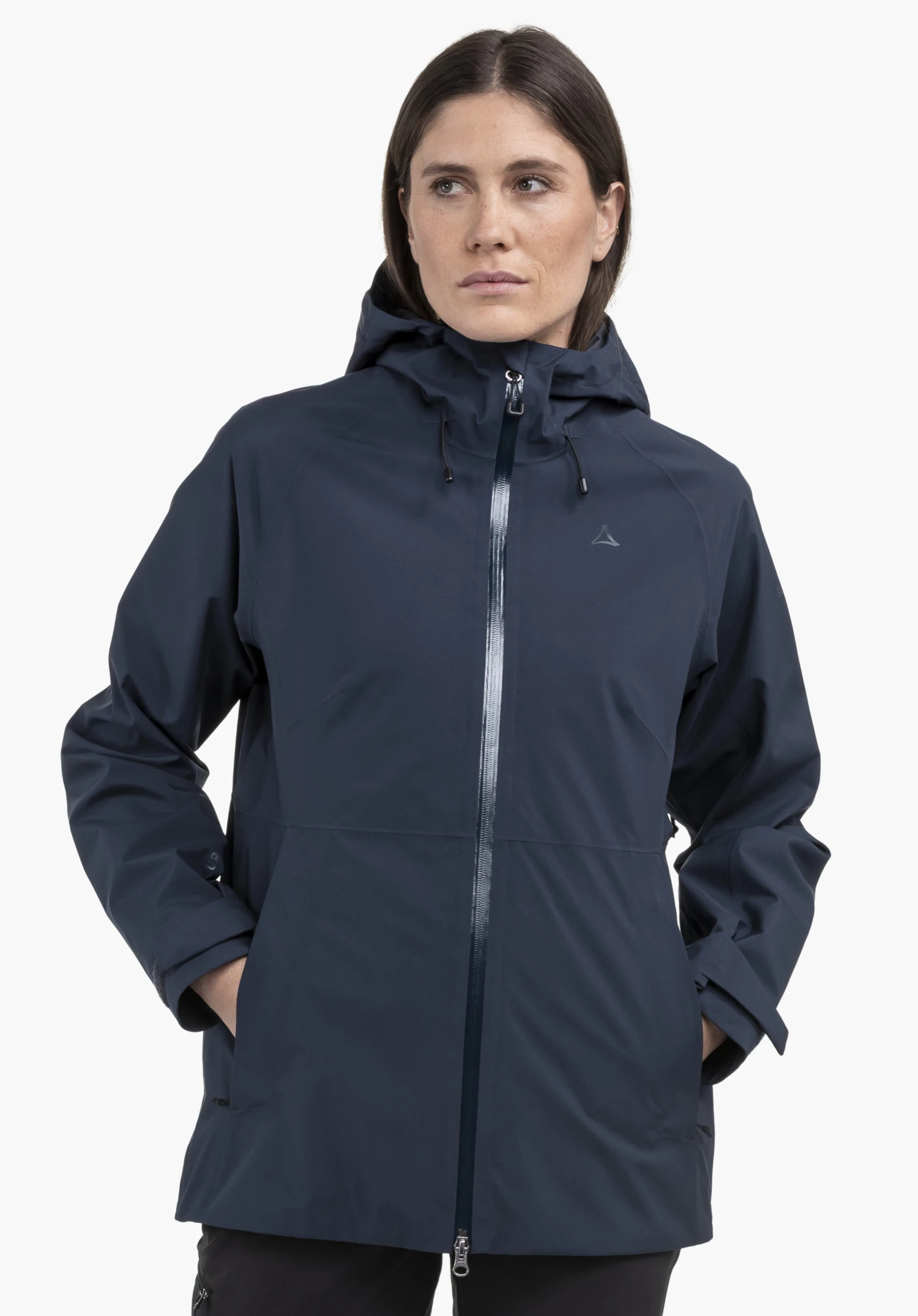 Jacket Style Mauku WMS. Un mannequin se tient de face avec les mains dans les poches de la veste bleue, sur laquelle le Schöffel-Logo est visible sur la poitrine, devant un fond neutre.