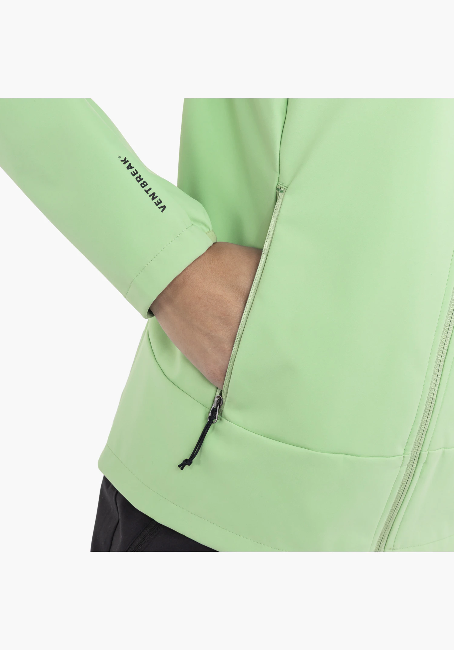 Softshell Jk Style Mirusha WMS zeigt eine Hand in der geöffneten seitlichen Reißverschlusstasche mit schwarzem Zupfer im grünen Stoff sowie den schwarzen Ventbreak-Schriftzug am Ärmel, Nahaufnahme vor weißem/neutralem Hintergrund.