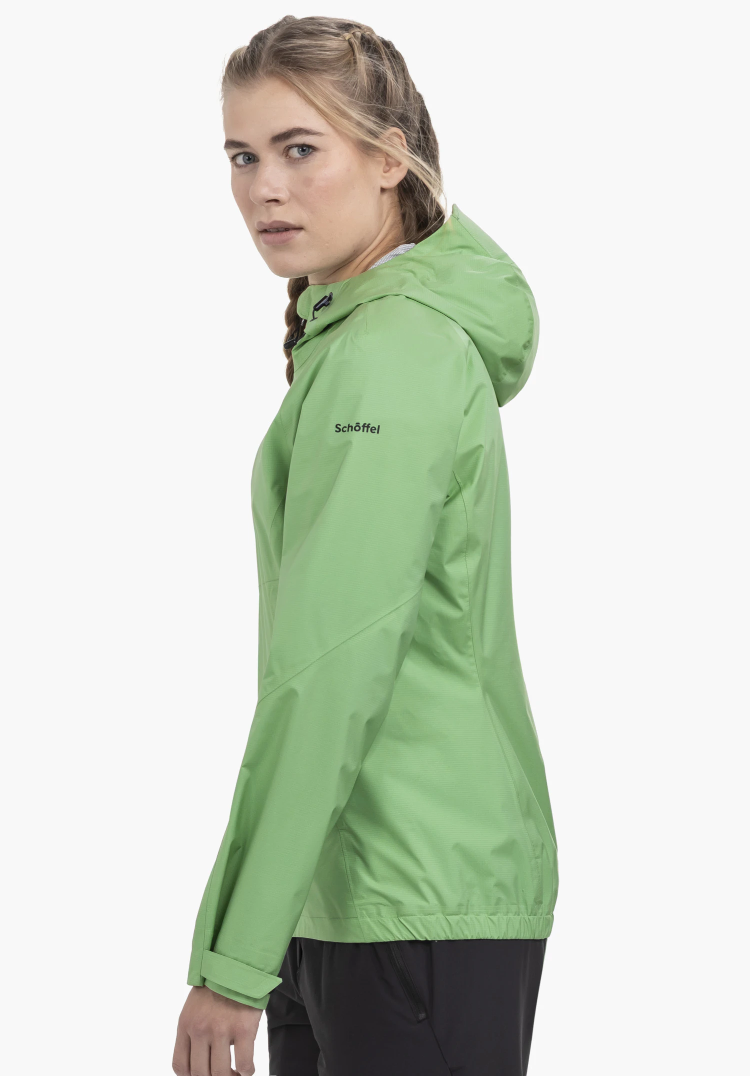 2.5L 3D Jacket Vistdal L in het groen. Het model staat zijwaarts voor een neutrale achtergrond en draagt de jas met de capuchon op. Het zwarte Schöffel-logo op de borst is goed zichtbaar.
