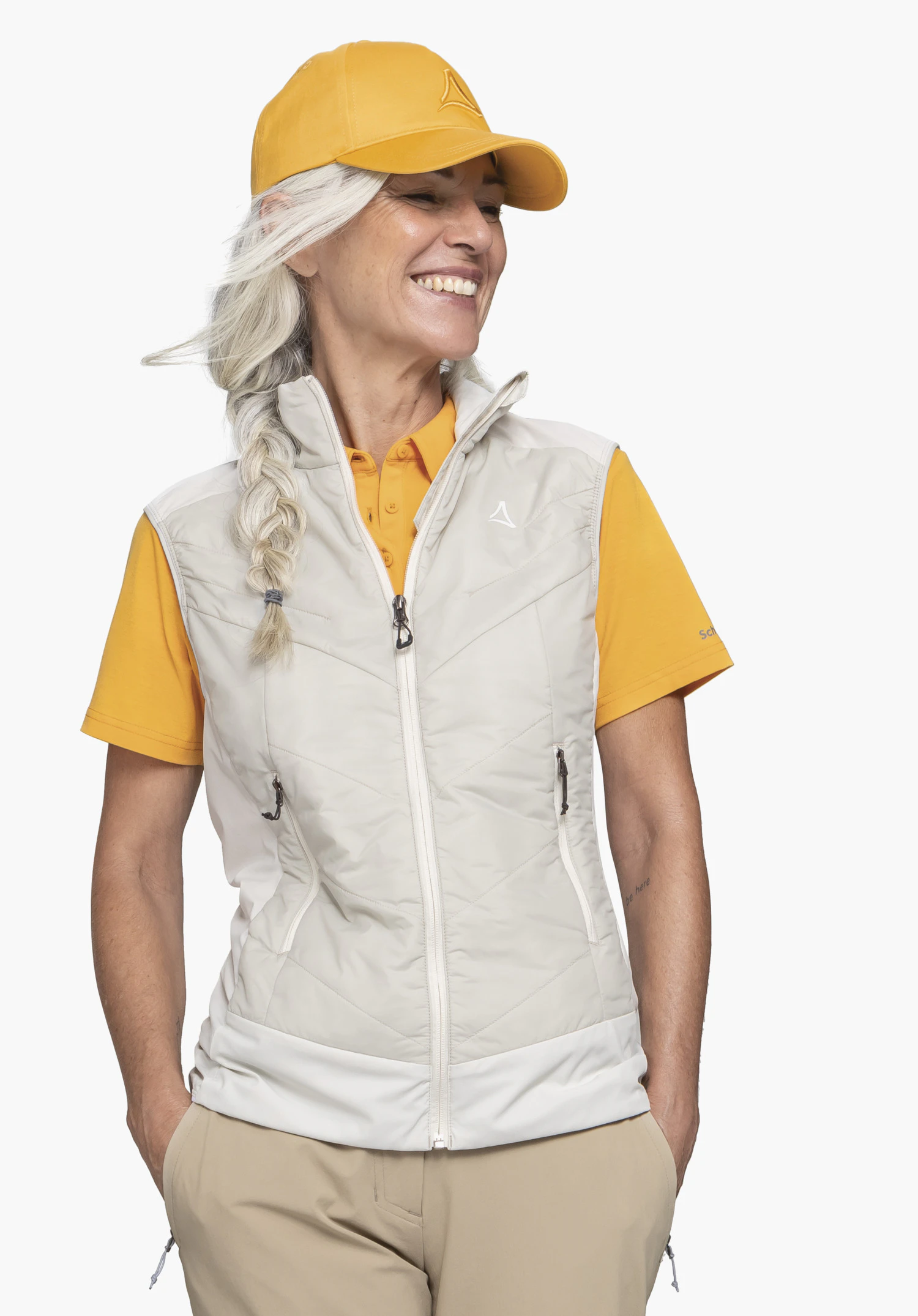 Hybrid Vt Style Blaueis WMS op een model dat frontaal staat en lachend opzij kijkt. Het gilet in de kleur natur toont het Schöffel-Logo op de linkerborst, gefotografeerd tegen een neutrale achtergrond.