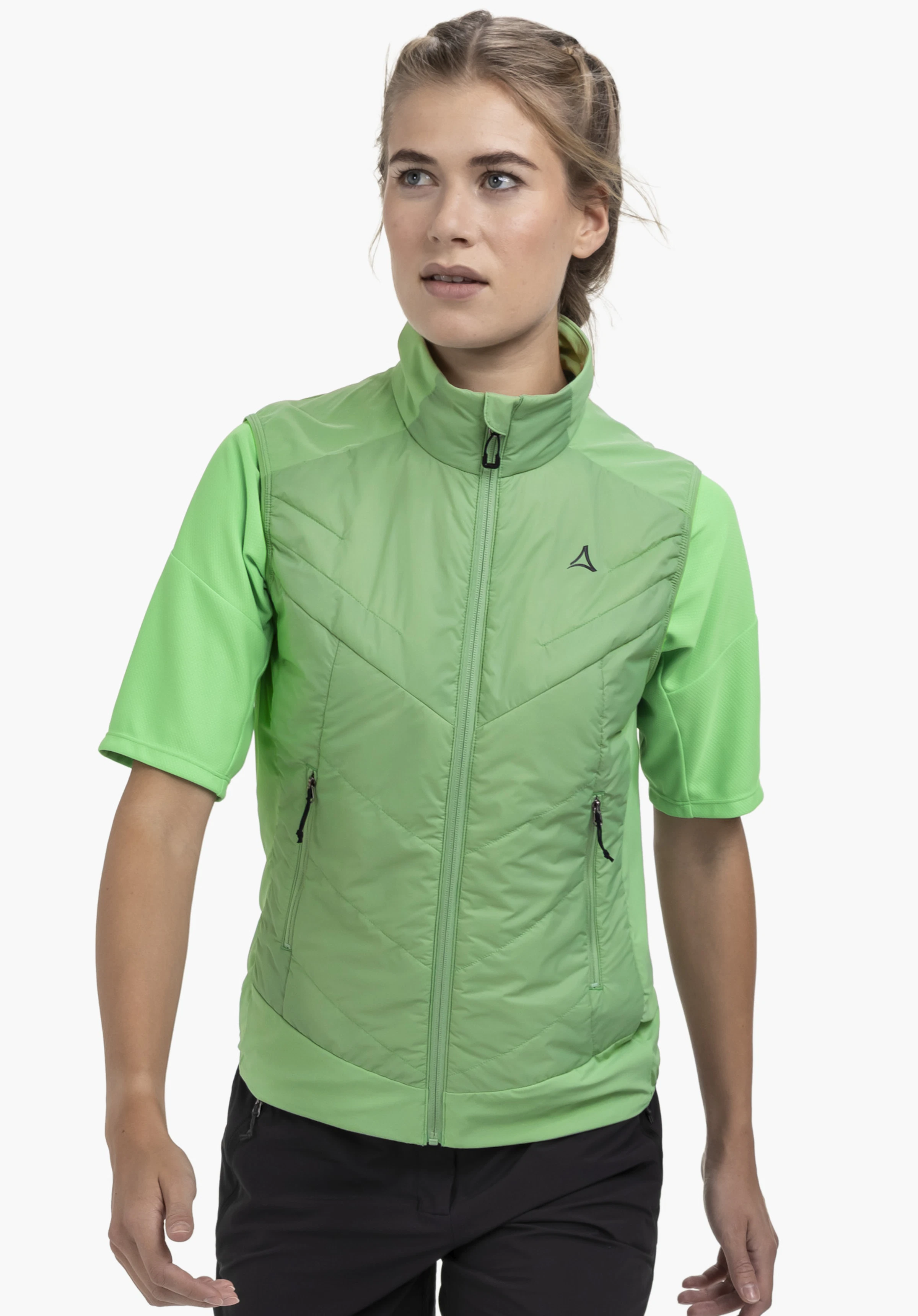 Hybrid Vt Style Blaueis WMS : Un mannequin se tient de face et porte le gilet à manches courtes vert avec une fermeture éclair, deux poches latérales et le logo Schöffel visible sur la poitrine gauche. La vue portée est présentée devant un fond neutre.