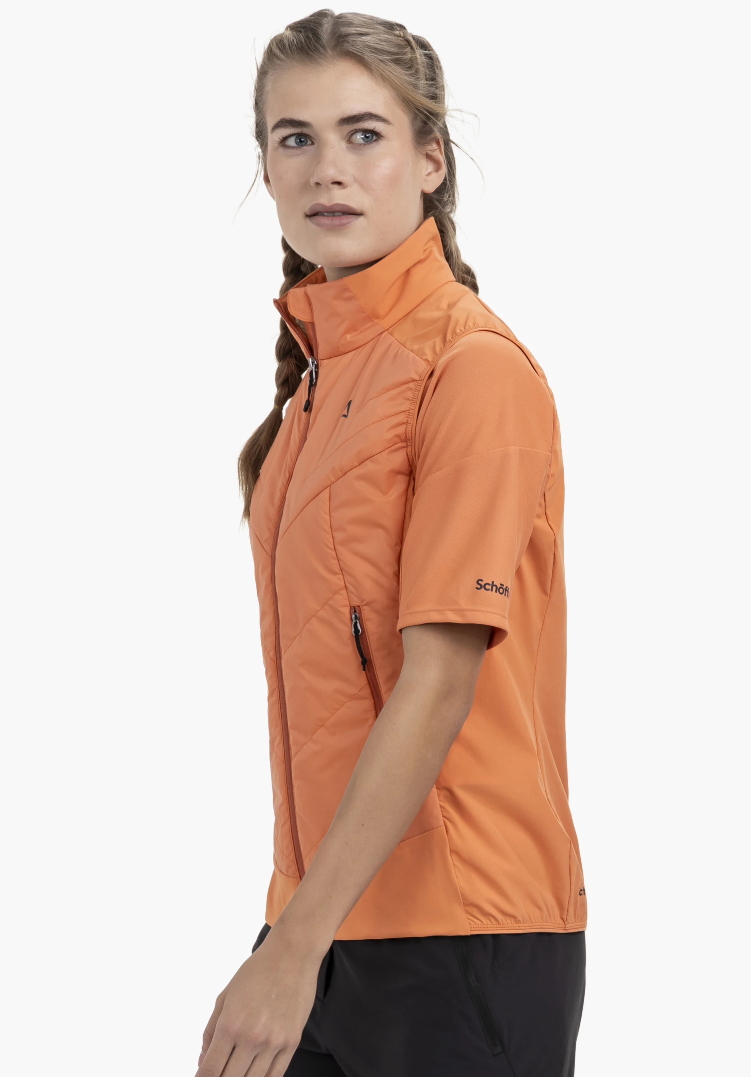 Hybrid Vt Style Blaueis WMS de couleur orange. Un mannequin se tient de profil et porte la veste à manches courtes avec un Schöffel-Logo visible sur la manche gauche devant un fond neutre.