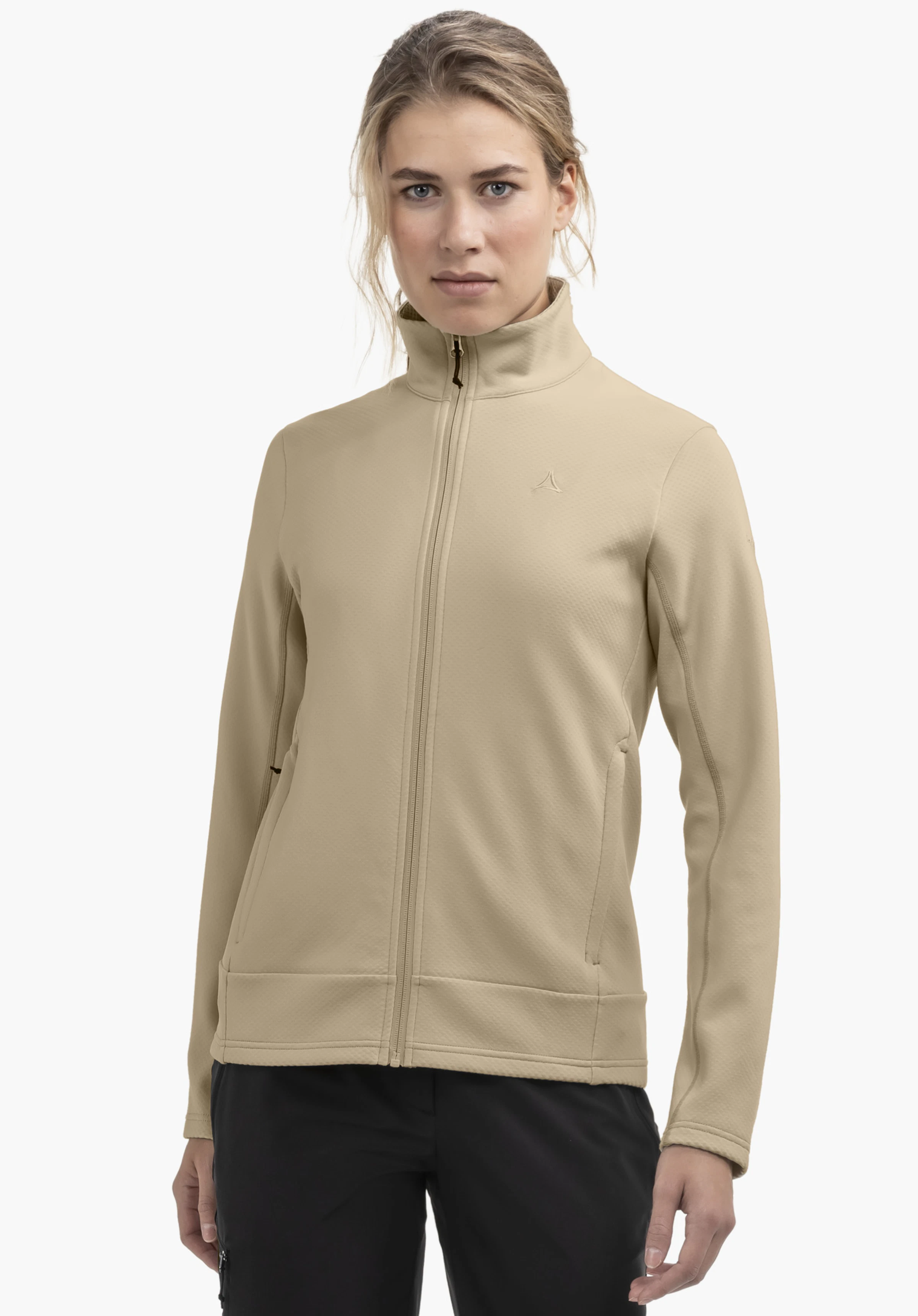 Fleece Jk Style Uriezzo WMS portée par un mannequin se tenant de face et regardant l'objectif. Elle porte la veste beige entièrement fermée. Le logo Schöffel est visible sur le côté gauche de la poitrine. L'image a été prise devant un fond neutre.