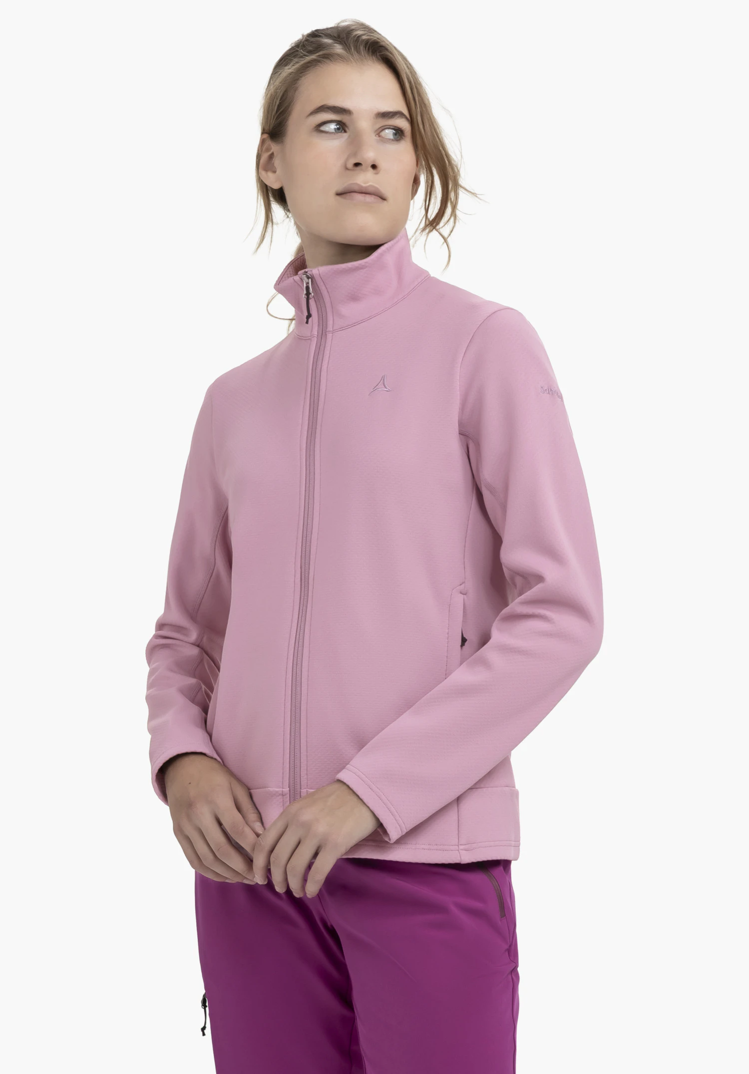 Fleece Jk Style Uriezzo WMS worn by a model standing slightly to the side in front of a neutral background. She showcases the pink jacket with a closed front zip, with the Schöffel logo clearly visible on the left chest.