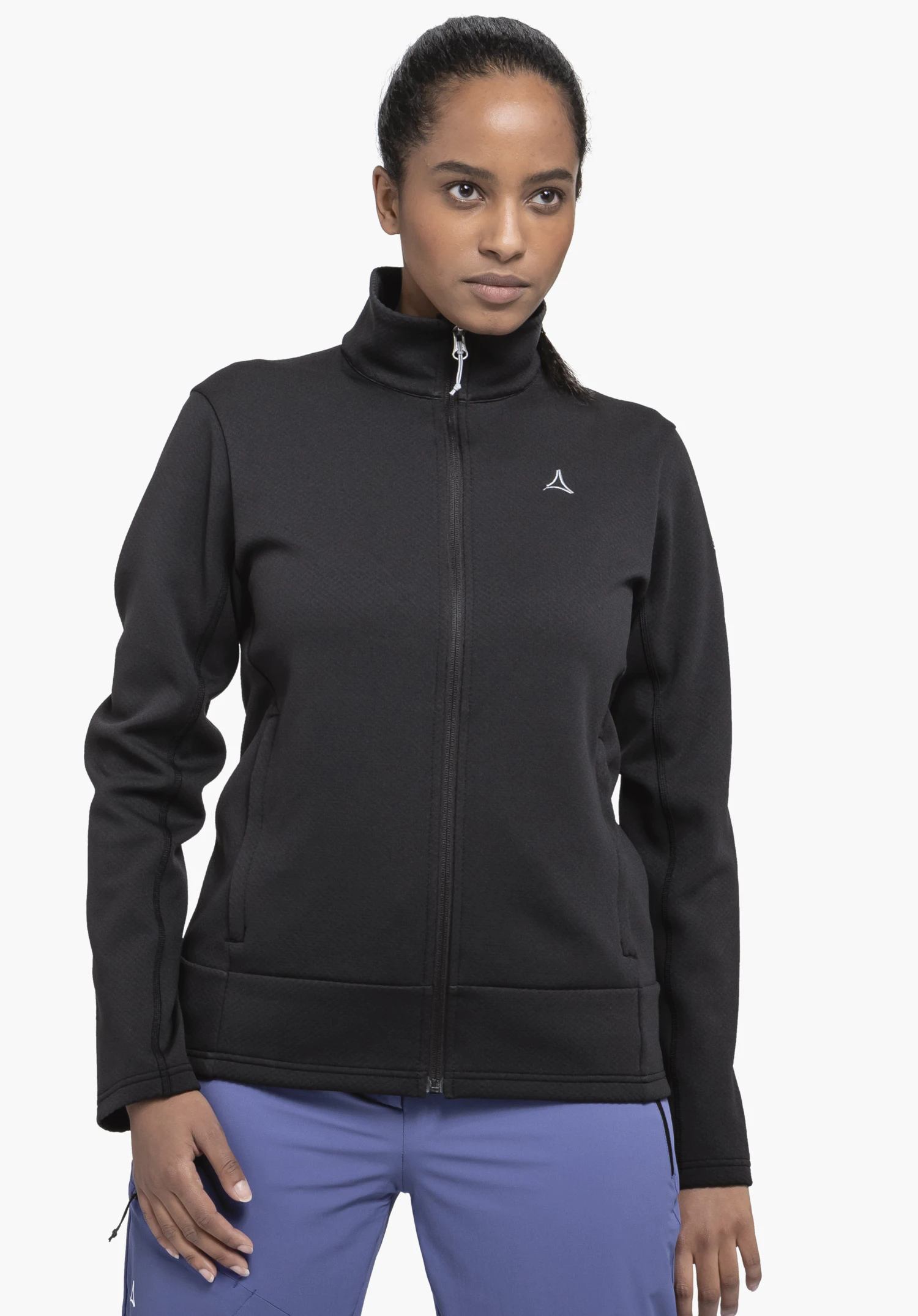 Fleece Jk Style Uriezzo WMS est portée par un mannequin vu de face. La veste en polaire noire présente un col montant, une fermeture zippée sur toute la longueur et le logo Schöffel sur la poitrine gauche. Le mannequin se tient devant un fond neutre.