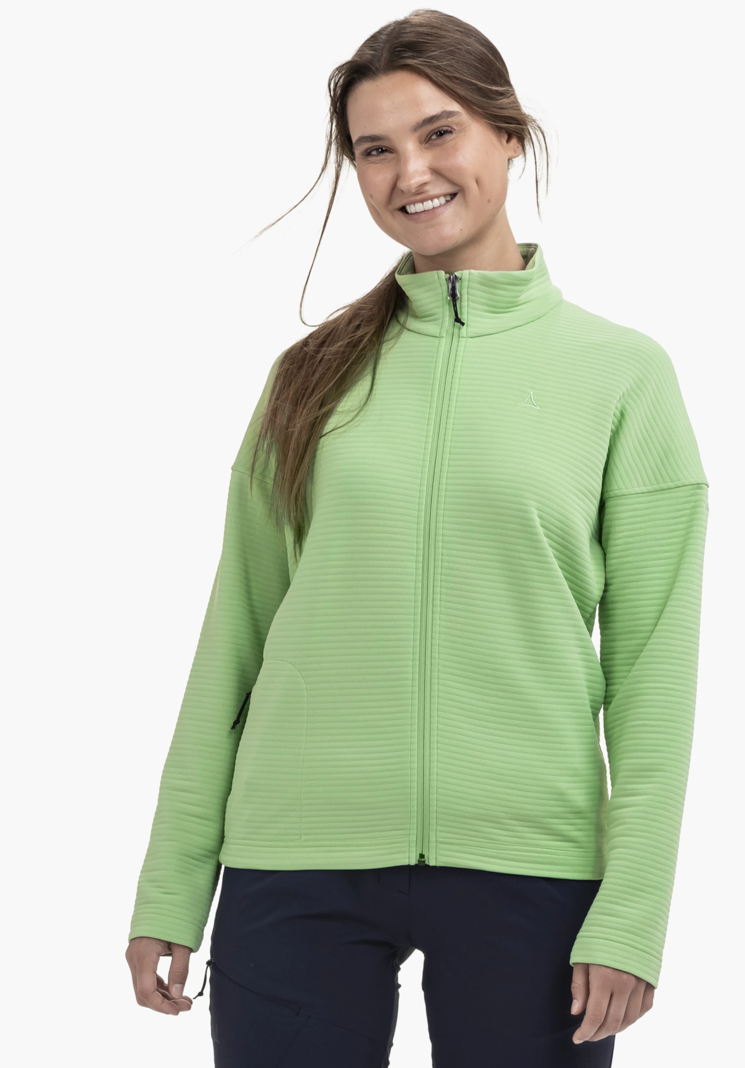 CIRC Fleece Jk Style Smue WMS wird von einem lächelnden Model getragen, das frontal steht. Die Fleecejacke in Grün ist geschlossen und zeigt ein dezentes Schöffel-Logo auf der Brust. Das Bild wurde vor einem neutralen Hintergrund aufgenommen.