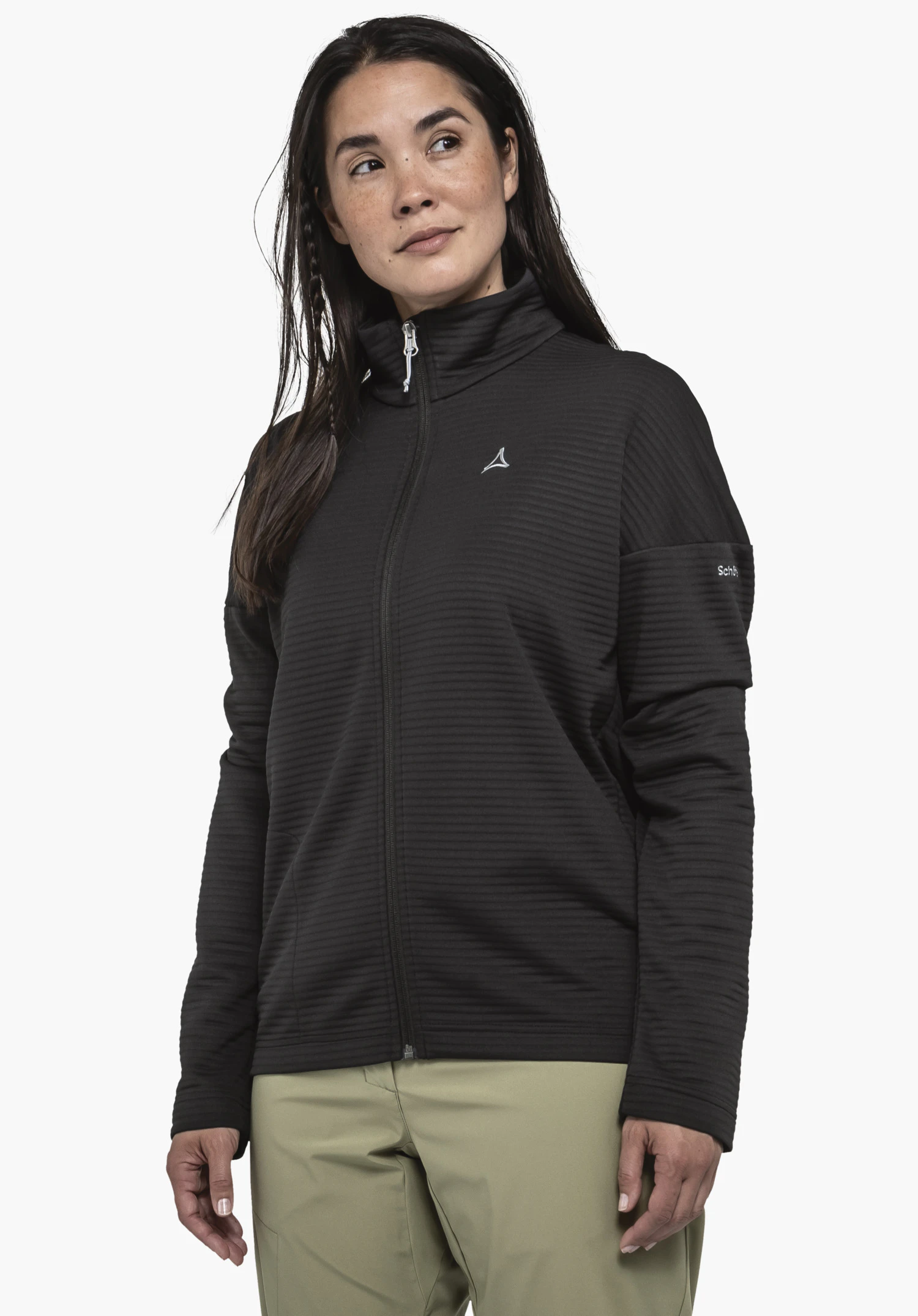 CIRC Fleece Jk Style Smue WMS. A model stands slightly turned to the side, wearing the black fleece jacket against a neutral background. The design features a fine horizontal ribbed structure, a high collar, and the Schöffel logo on the left chest as well as on the sleeve.