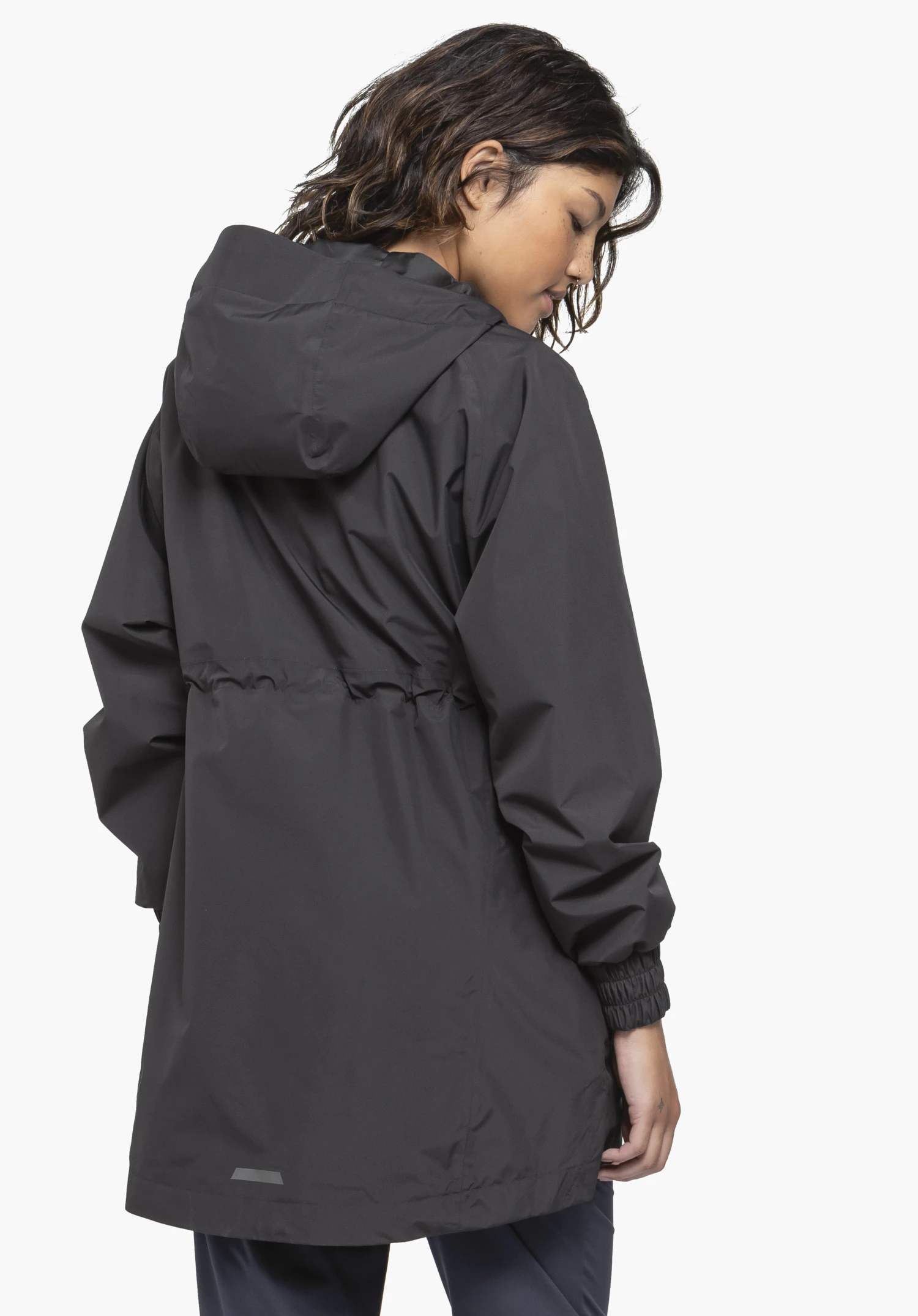 Parka Style Bohorok WMS is worn by a model standing slightly sideways in a back view. You can see the black parka with a hood and gathered waist against a neutral background.