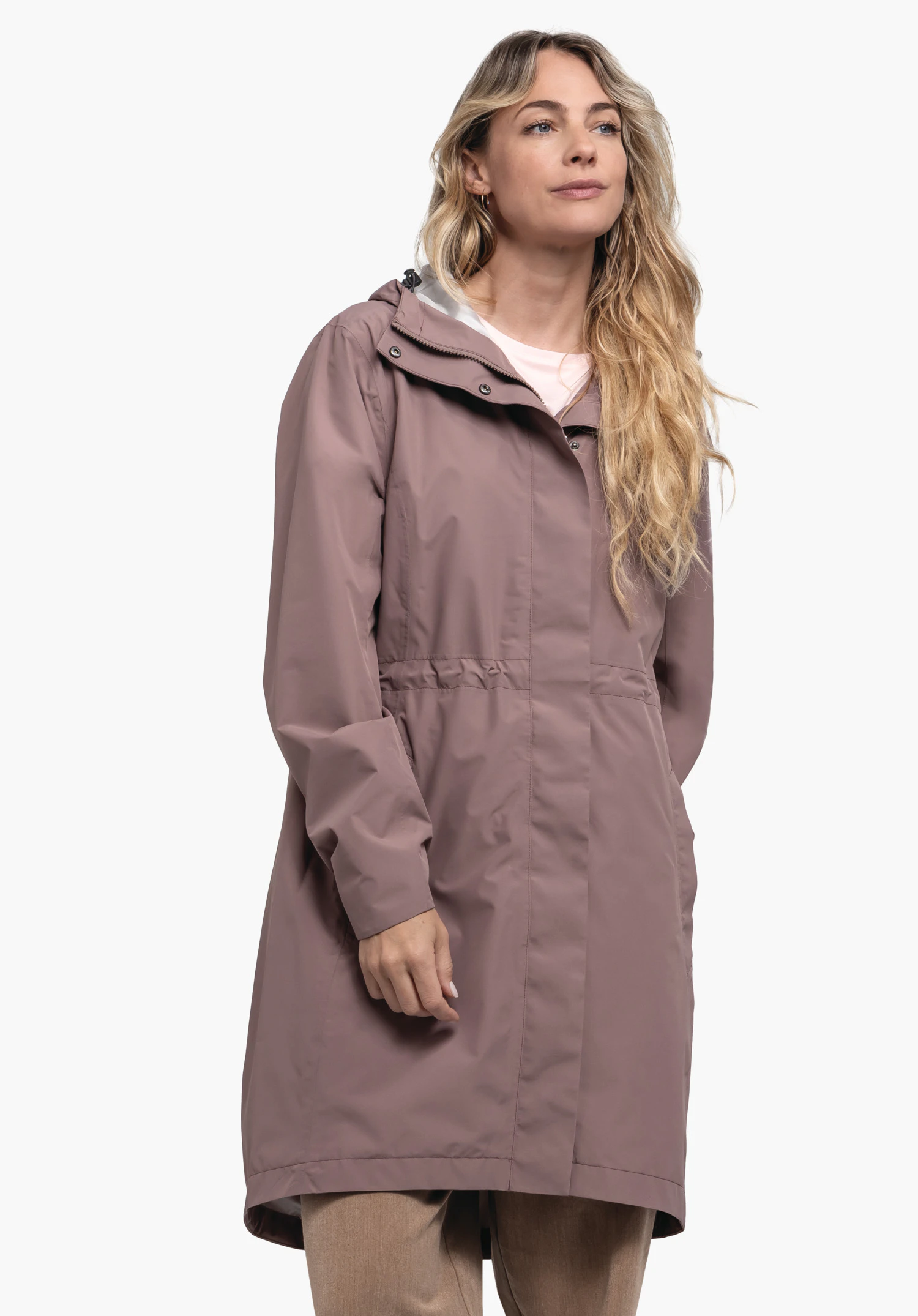 Coat Style Bohorok WMS in brown: A blonde model stands in a slightly angled pose against a neutral background. The minimalist look highlights the elegant design of the coat, while the subtle Schöffel logo rounds off the premium quality.
