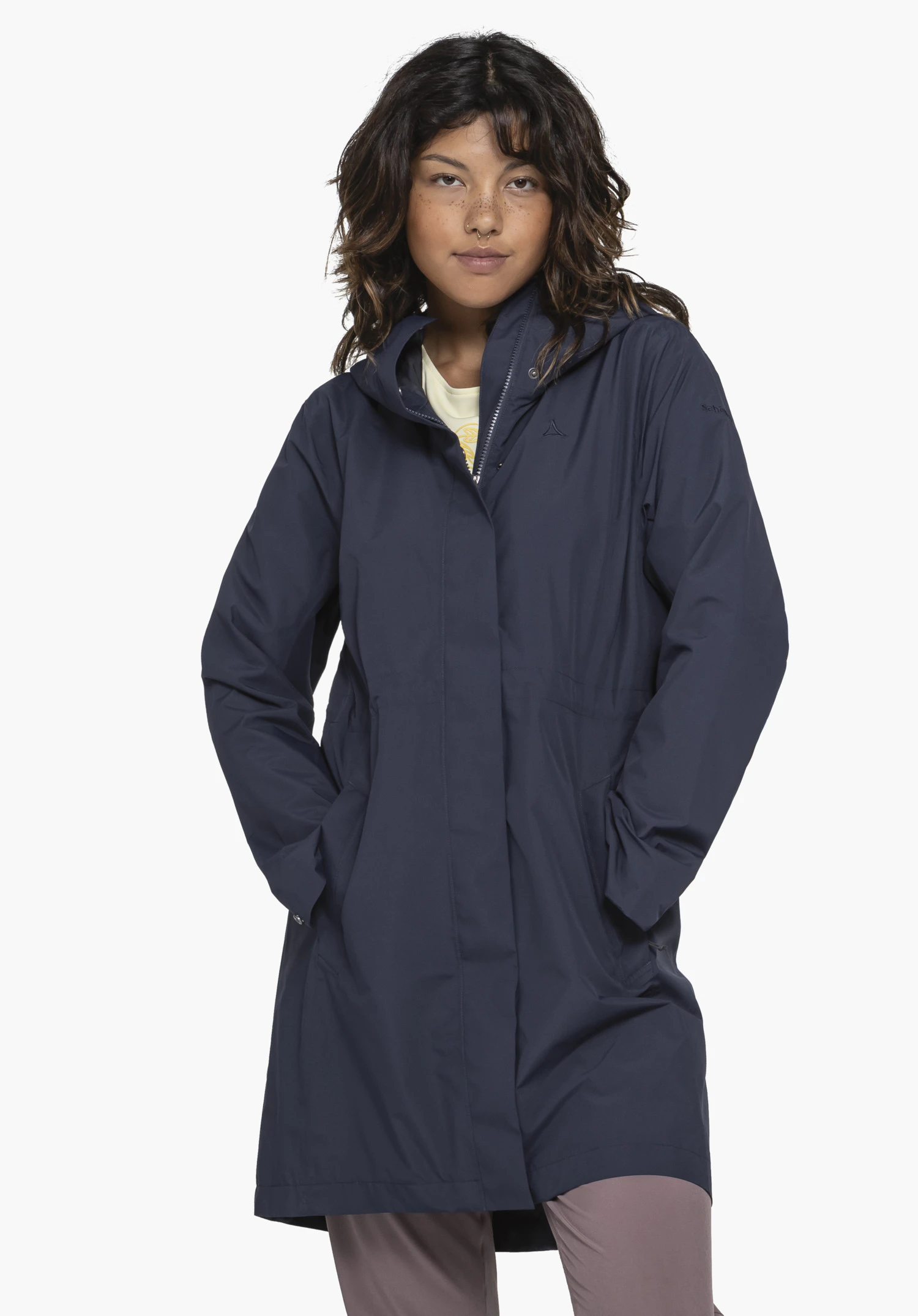 Coat Style Bohorok WMS en bleu. Le modèle pose de face devant un fond neutre, portant le manteau les mains dans les poches. Le logo Schöffel discret est visible au niveau de la poitrine.