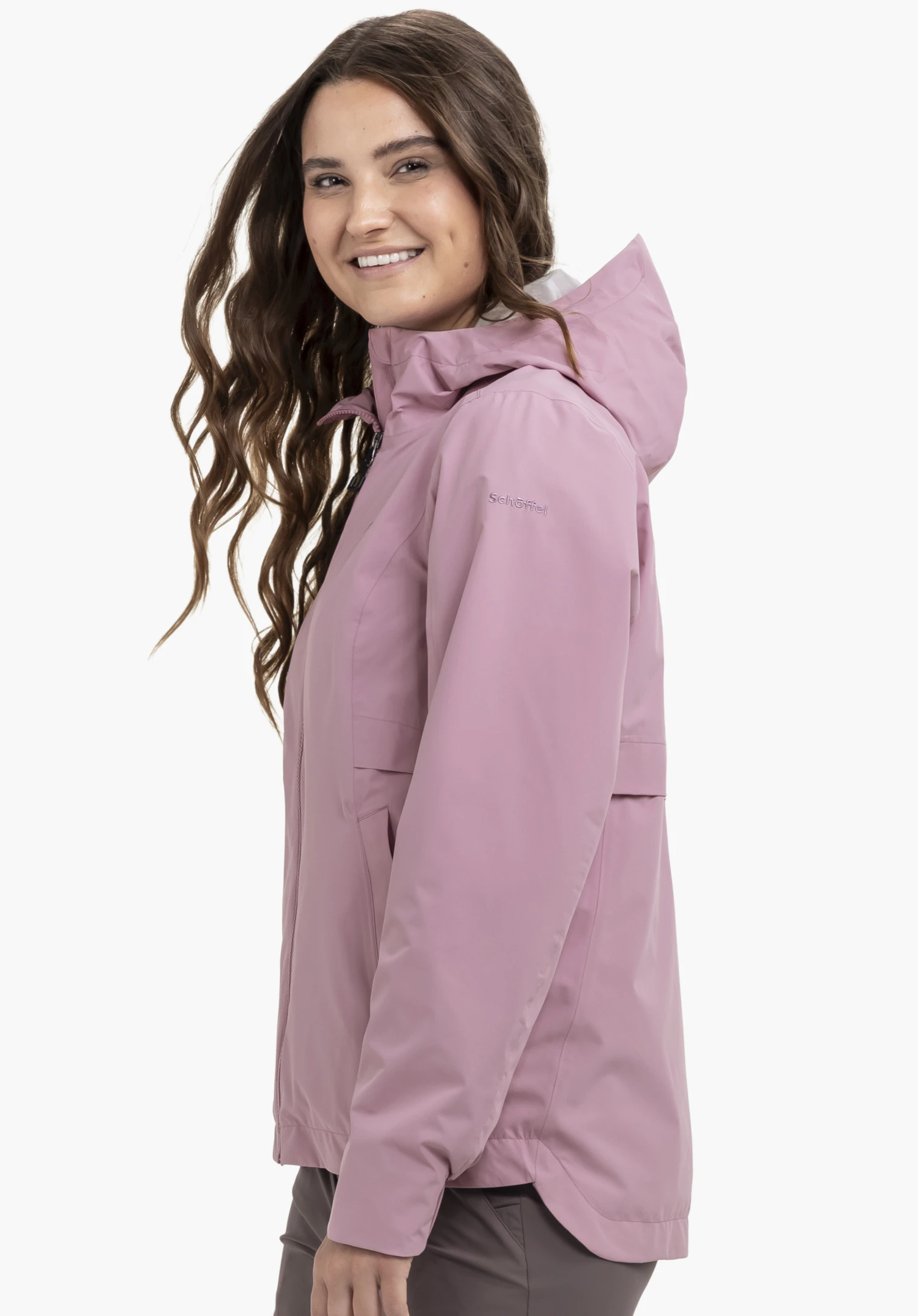 Jacket Style Bohorok WMS in soft pink: A smiling model stands sideways against a neutral background, showcasing the jacket with the subtle Schöffel logo clearly visible on the upper arm.