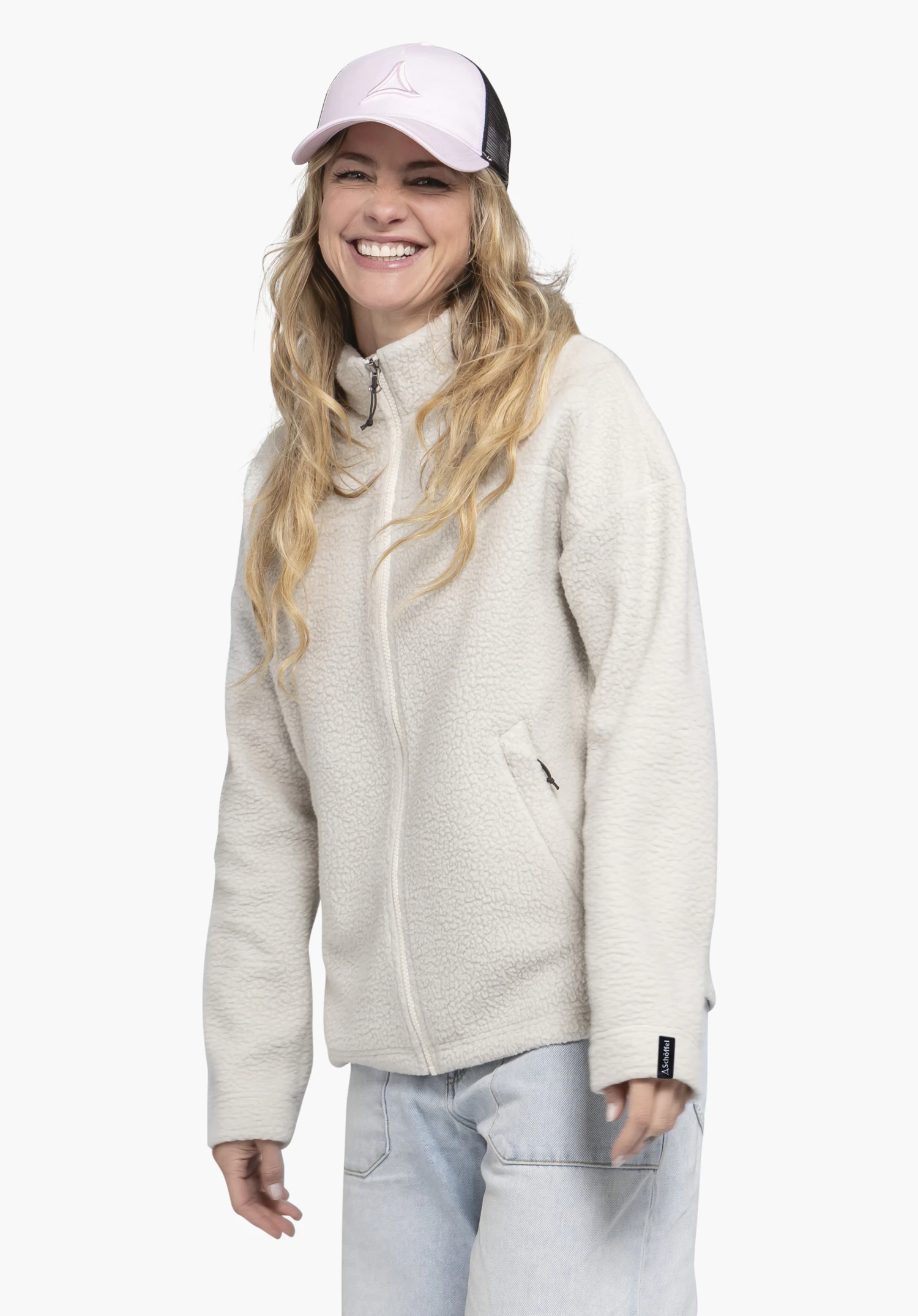 CIRC Fleece Jk Style Purga WMS in the color natur features a smiling woman in a frontal view against a neutral background. The fleece jacket impresses with its cozy texture and a small Schöffel-Logo on the cuff, highlighting its sporty look.